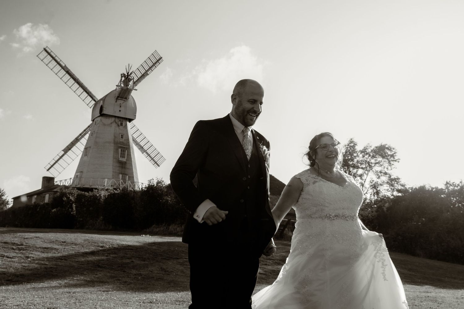 Silhouetted wedding portraits with traditional windmill backdrop at sunset.