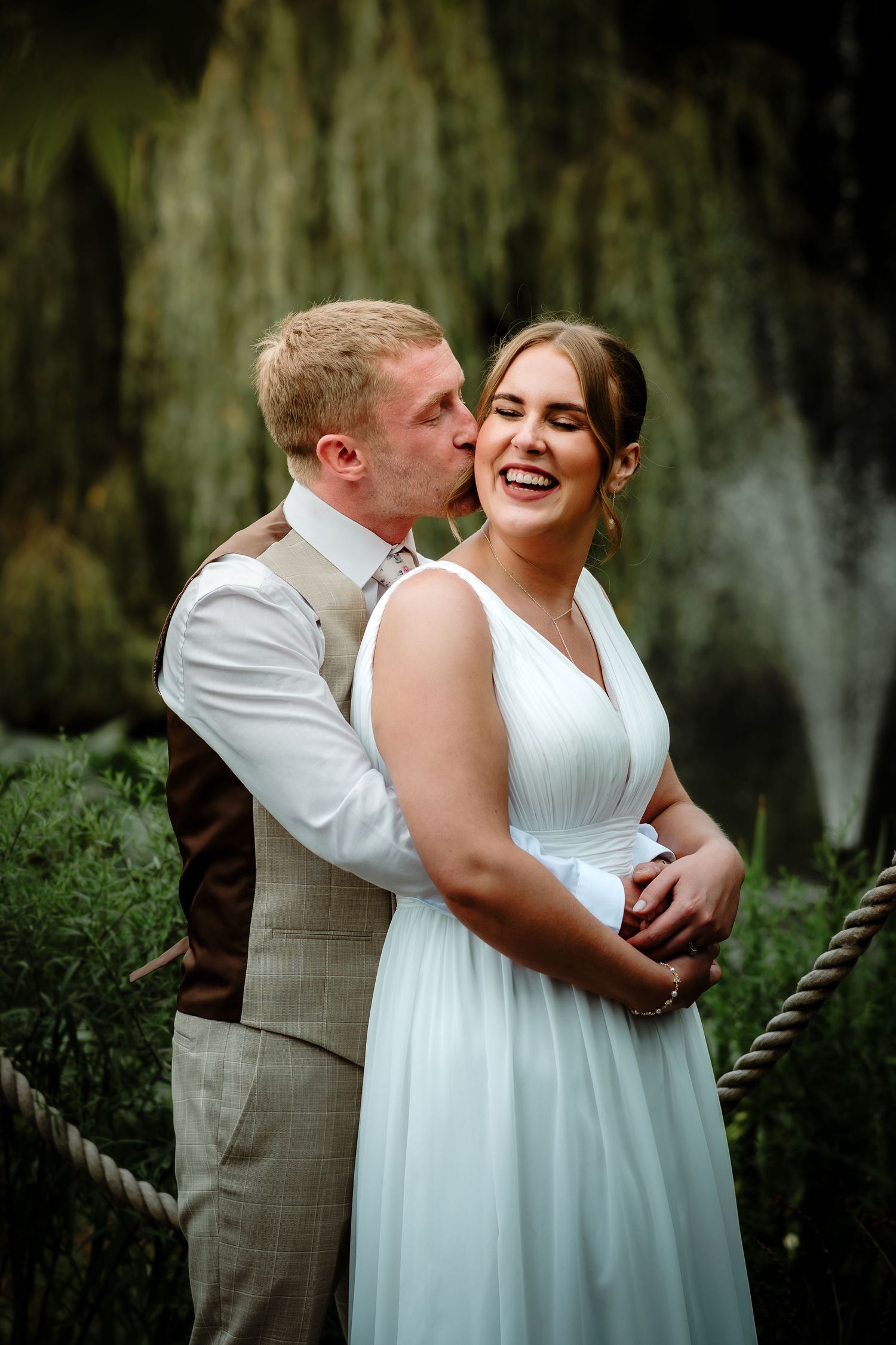Joyful wedding couple sharing intimate moments in garden setting with soft lighting.