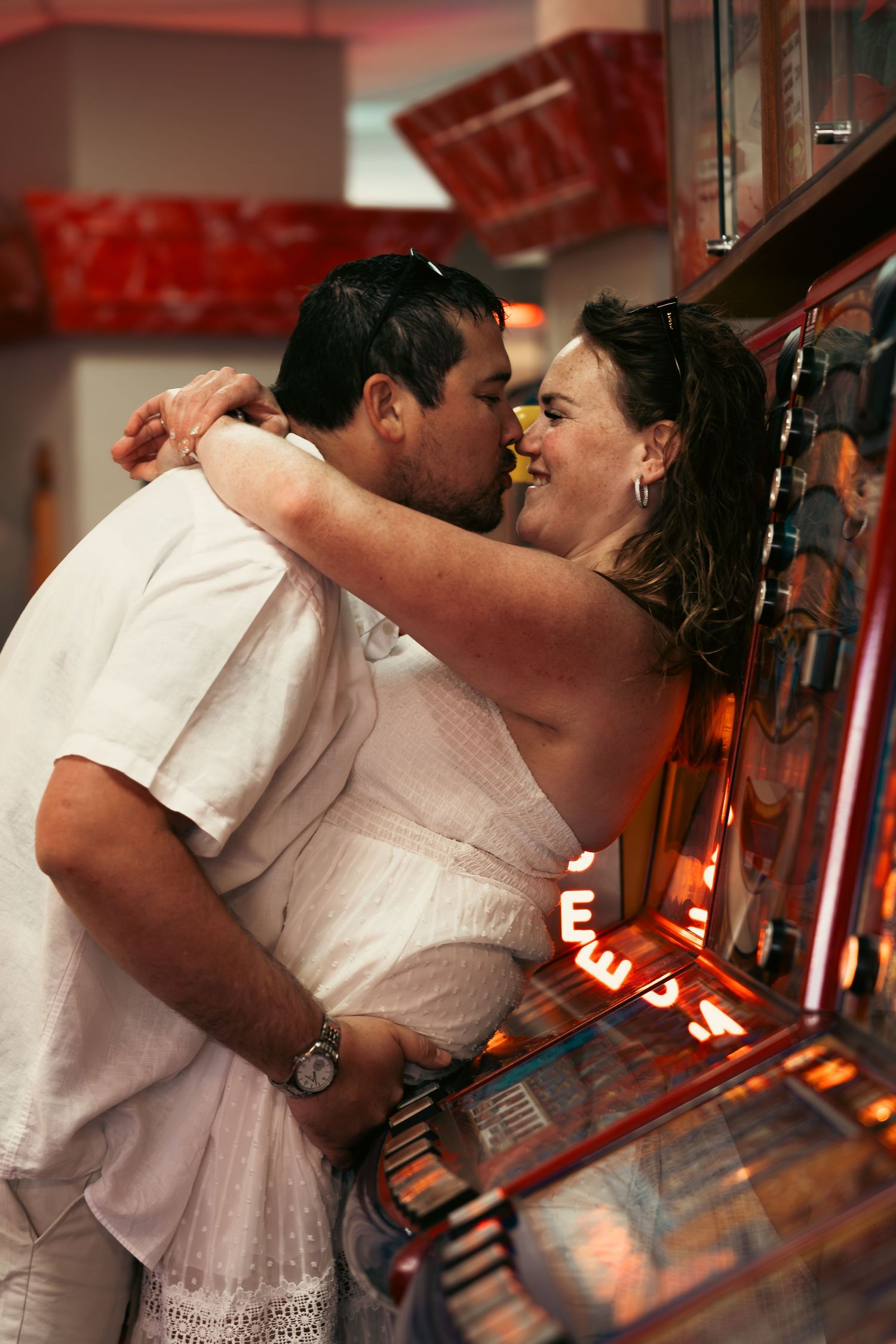 Intimate moment captured in red ambient lighting near bar display.