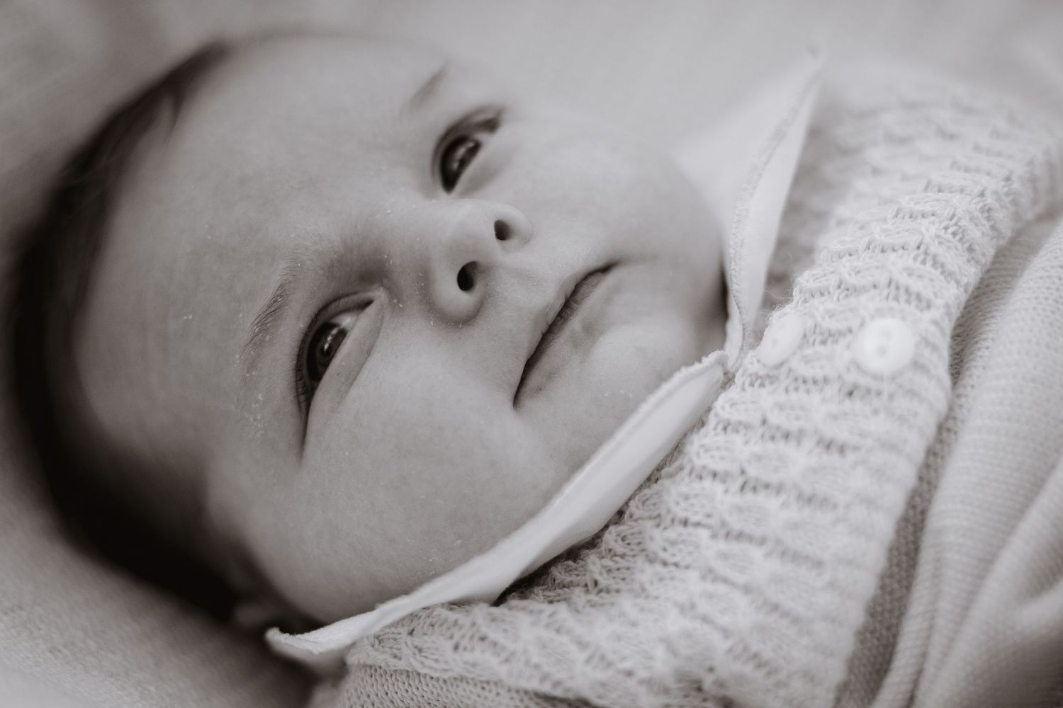 Sweet close-up portraits of a baby's face against soft white fabric.