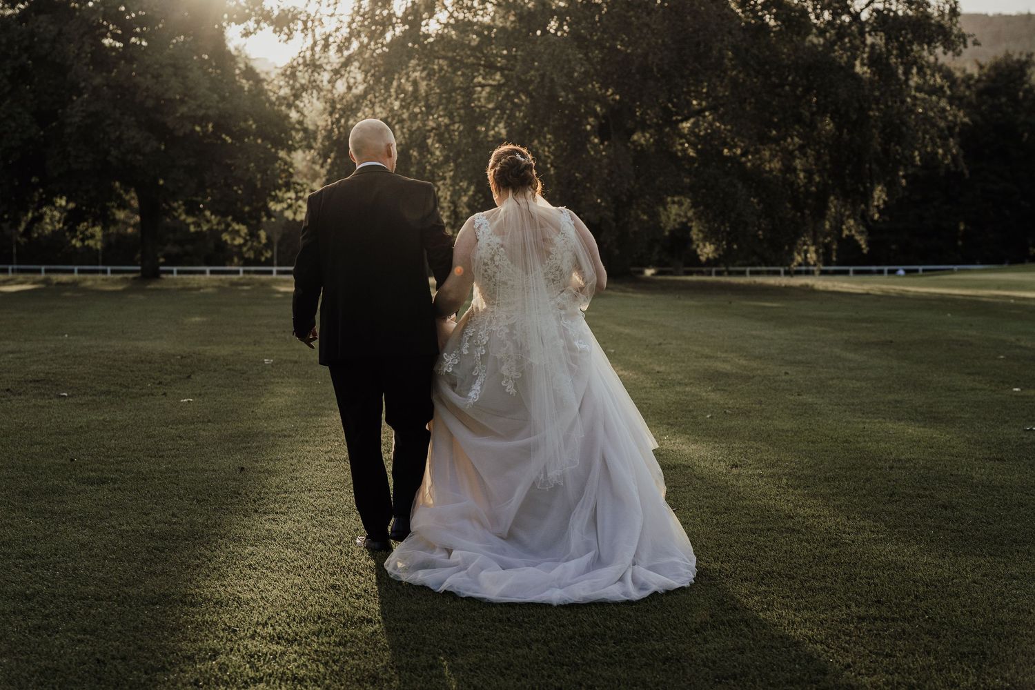 Silhouetted couple walking together on grassy lawn during golden hour sunset.