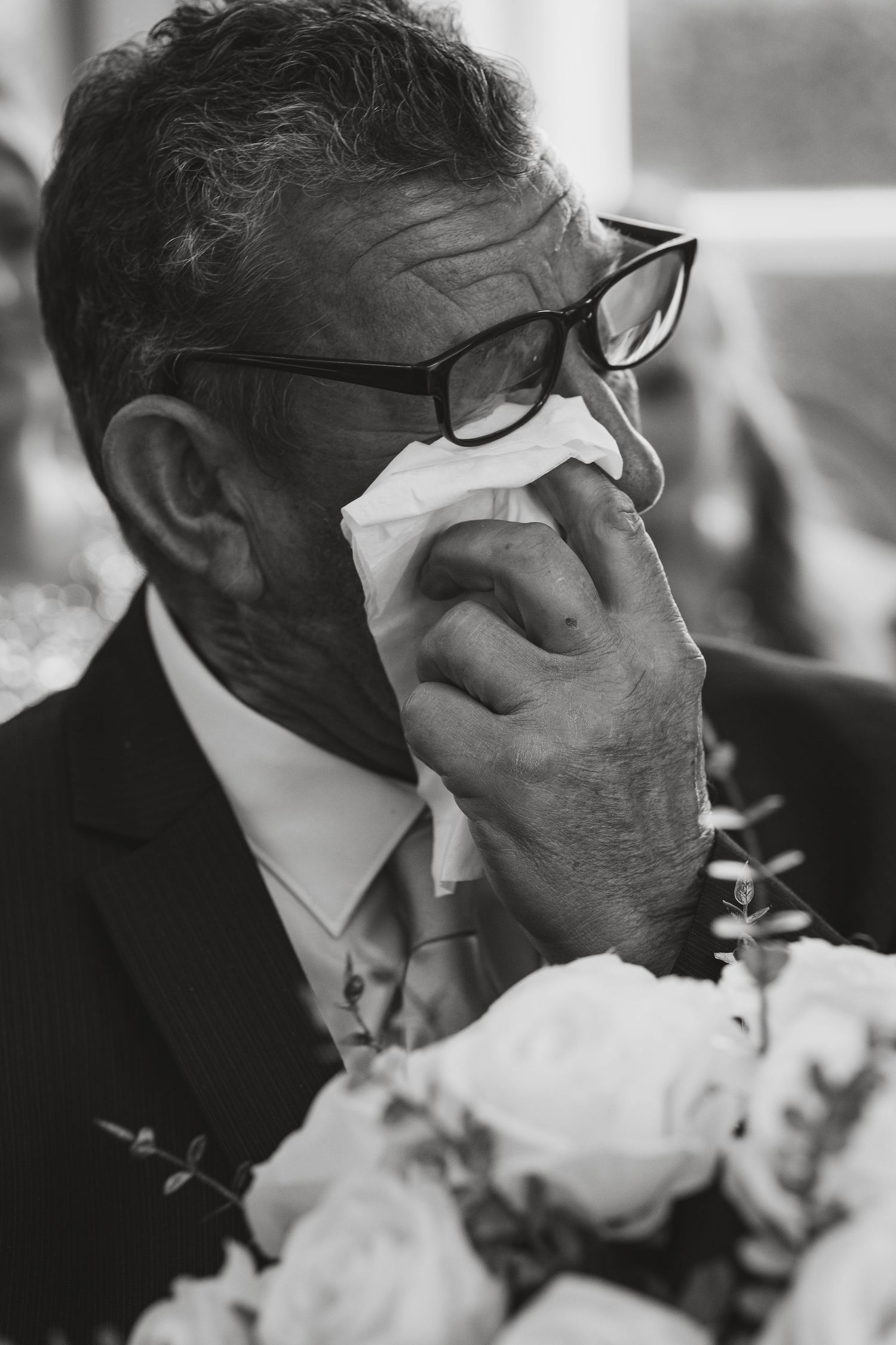 Black and white close-up shots of someone smelling wedding bouquet flowers.