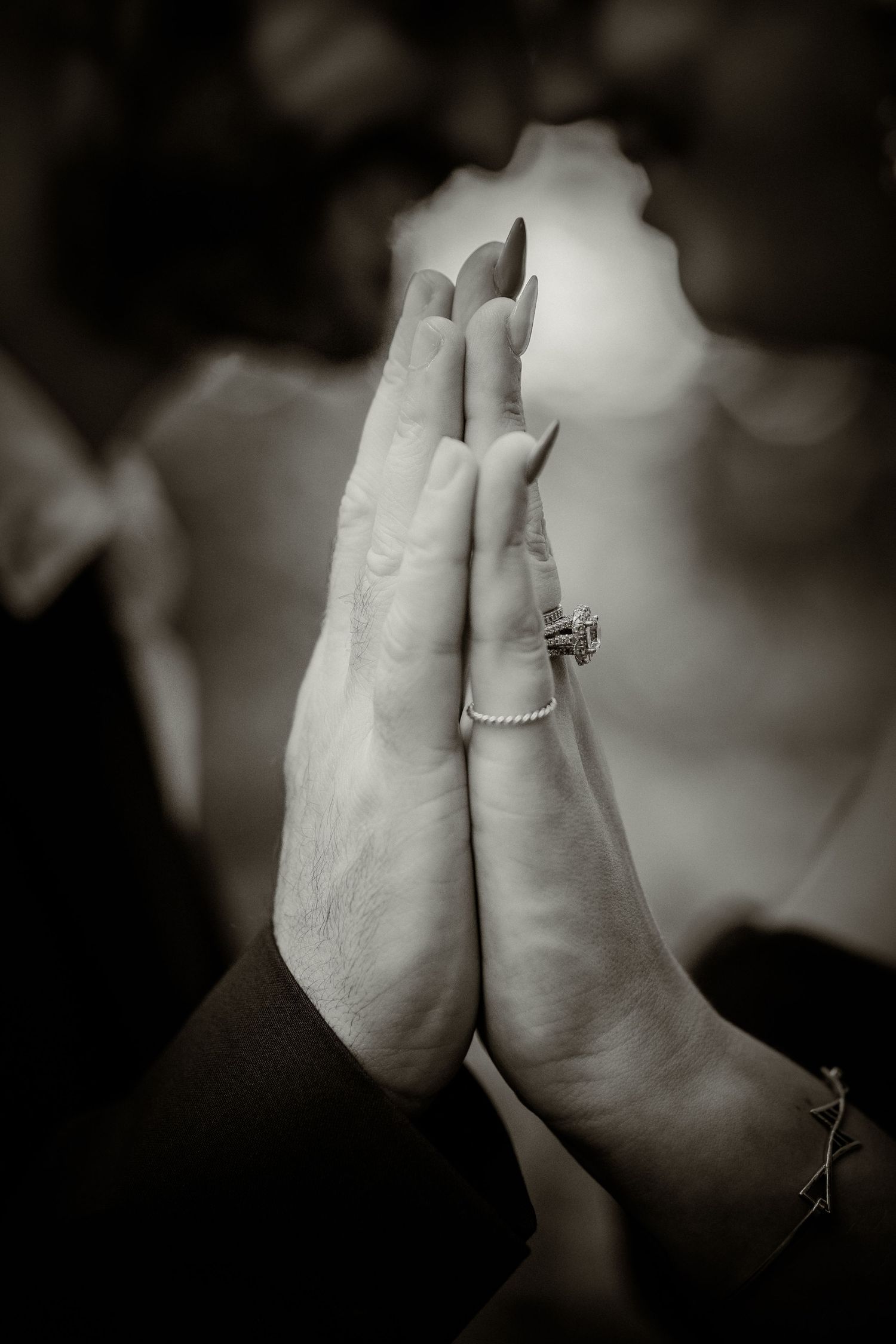 Close-up black and white photo of hands showing an engagement ring.