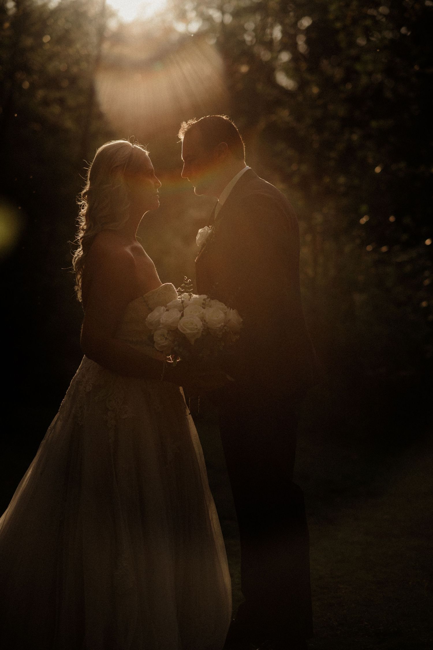 Silhouetted wedding couple embracing during golden hour sunset photoshoot.