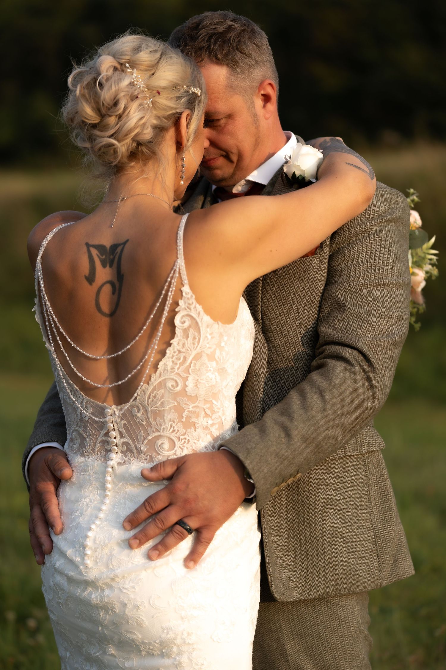 Intimate sunset portrait of newlyweds embracing in warm evening light.