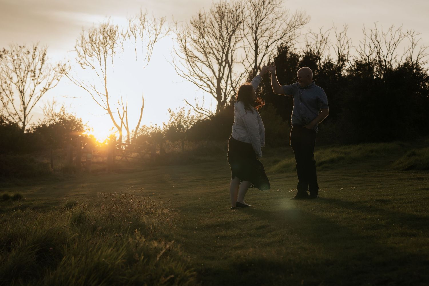 Silhouettes of people against a dramatic sunset sky on a hilltop.