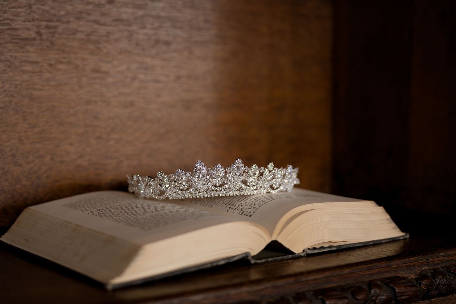 Crystal tiara rests elegantly on an open book in dramatic lighting.
