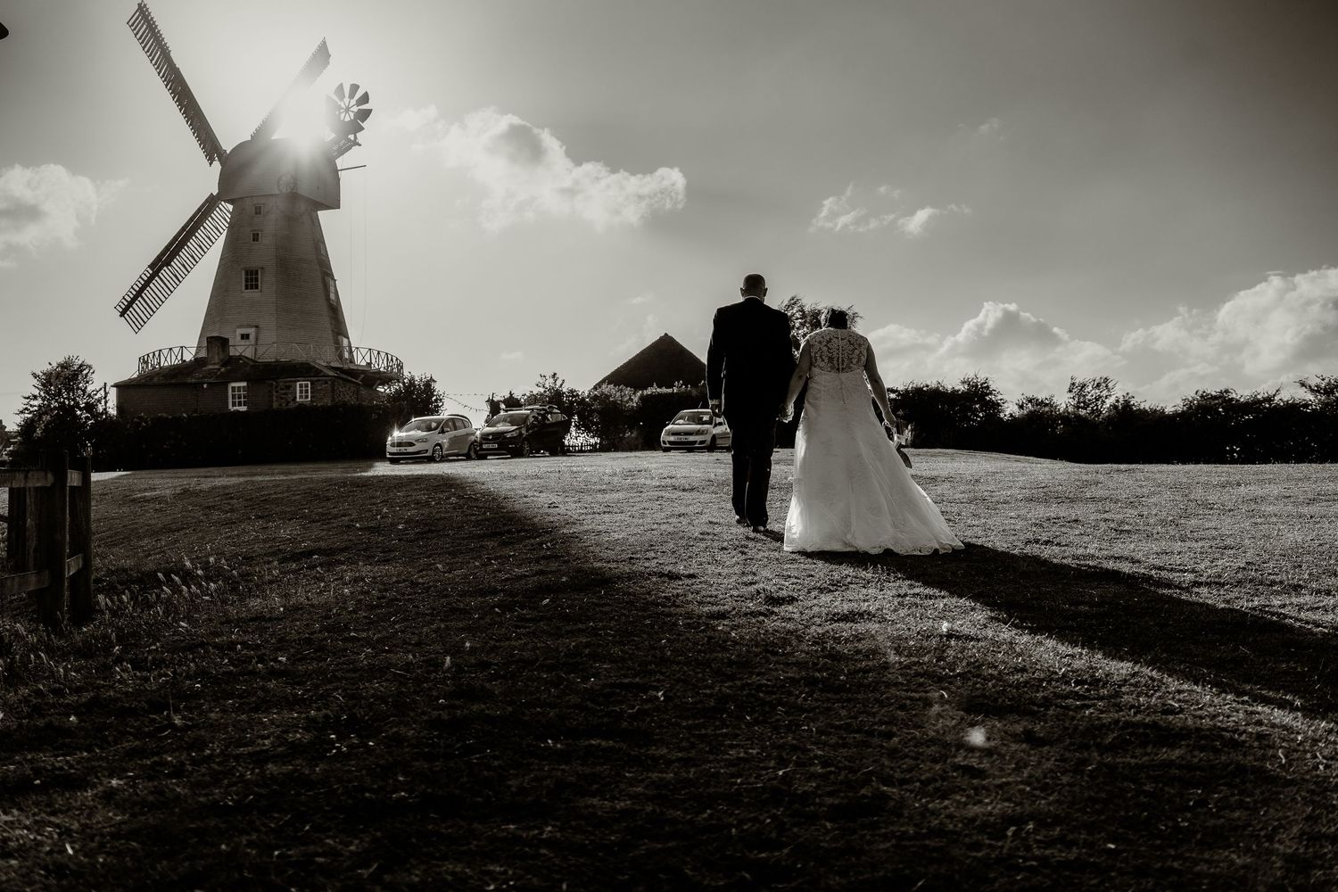 Dramatic black and white landscape featuring windmills against cloudy sky.