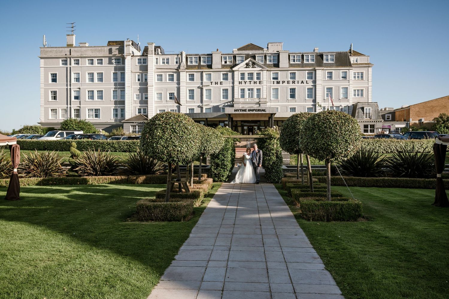 Elegant white mansion with manicured gardens and stone pathways.