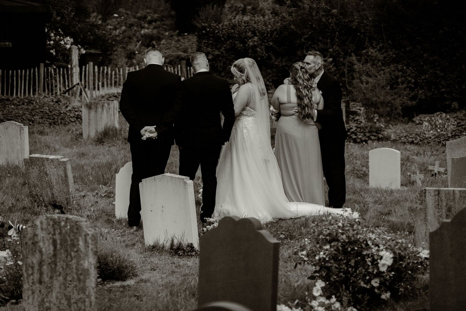 Wedding party poses together outdoors in formal attire against a natural backdrop.