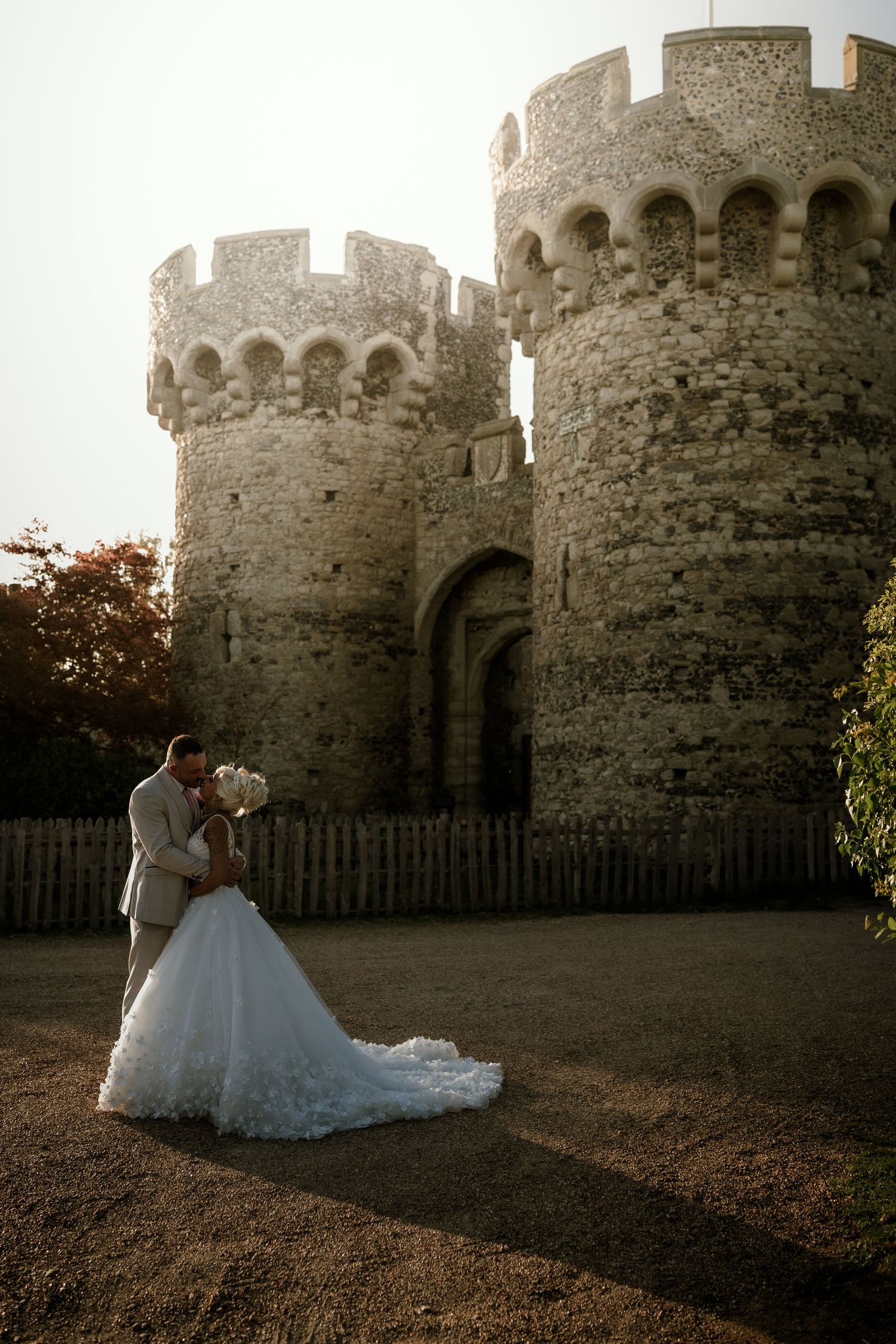 Romantic wedding portraits against a historic stone castle at sunset.