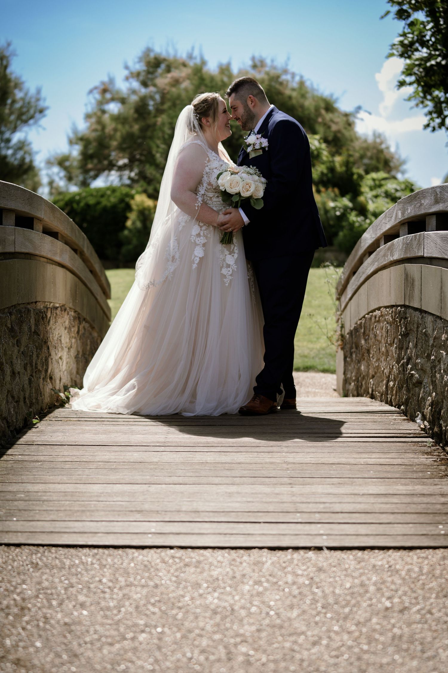 Romantic wedding photos taken on a wooden bridge with soft natural lighting.
