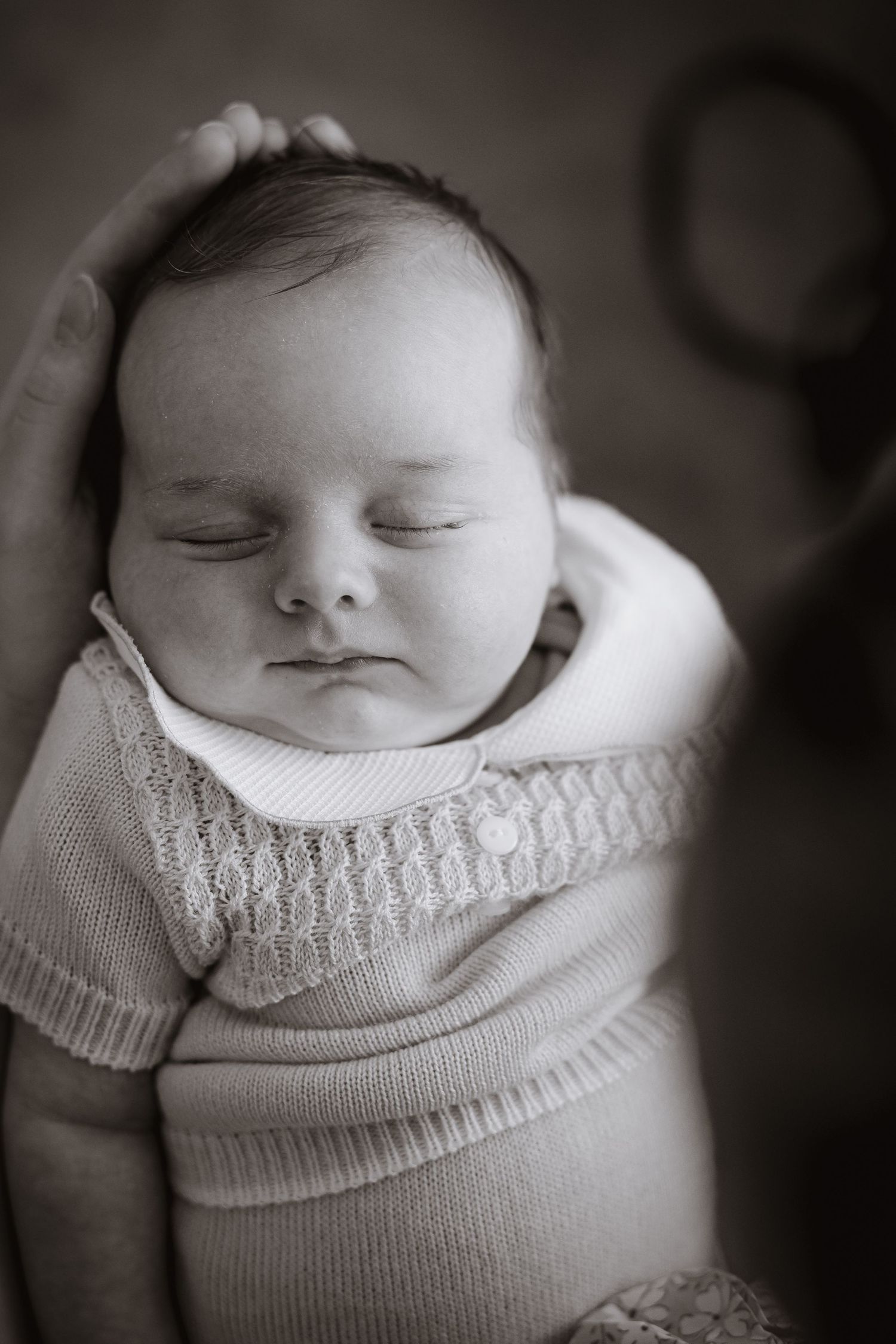 Peaceful black and white portrait of a sleeping newborn in a knit sweater.