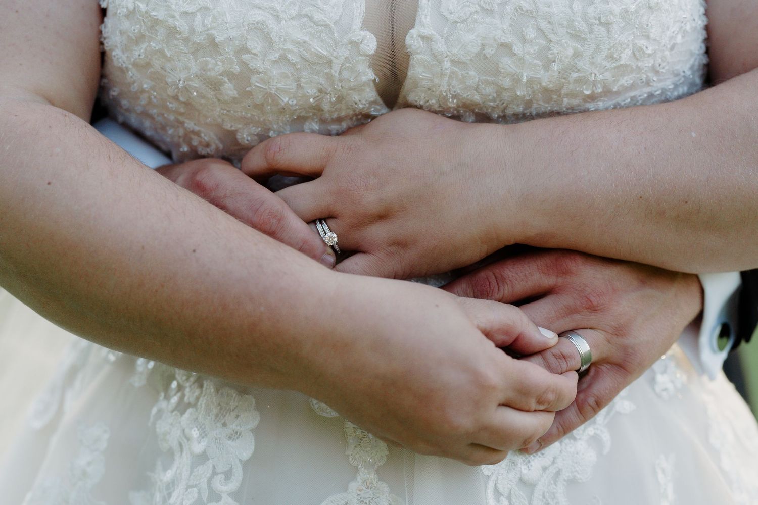 Close-up detail of hands holding rings during an elegant wedding ceremony.