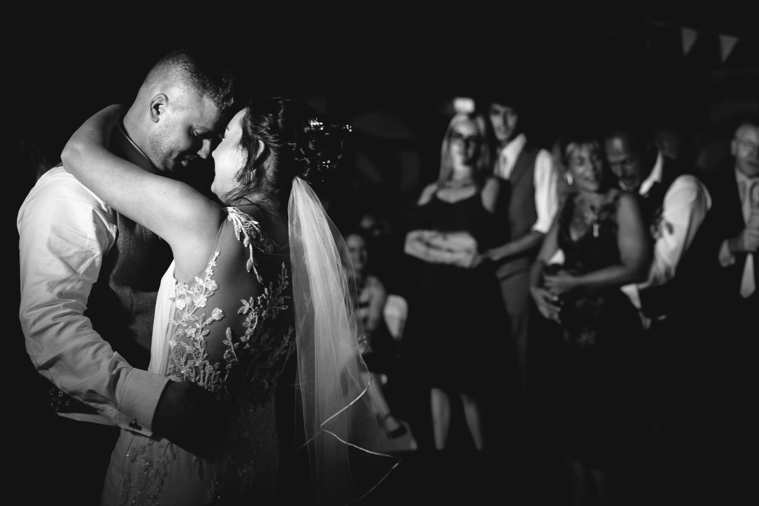 Wedding reception dance floor with silhouettes of guests celebrating in the dark.