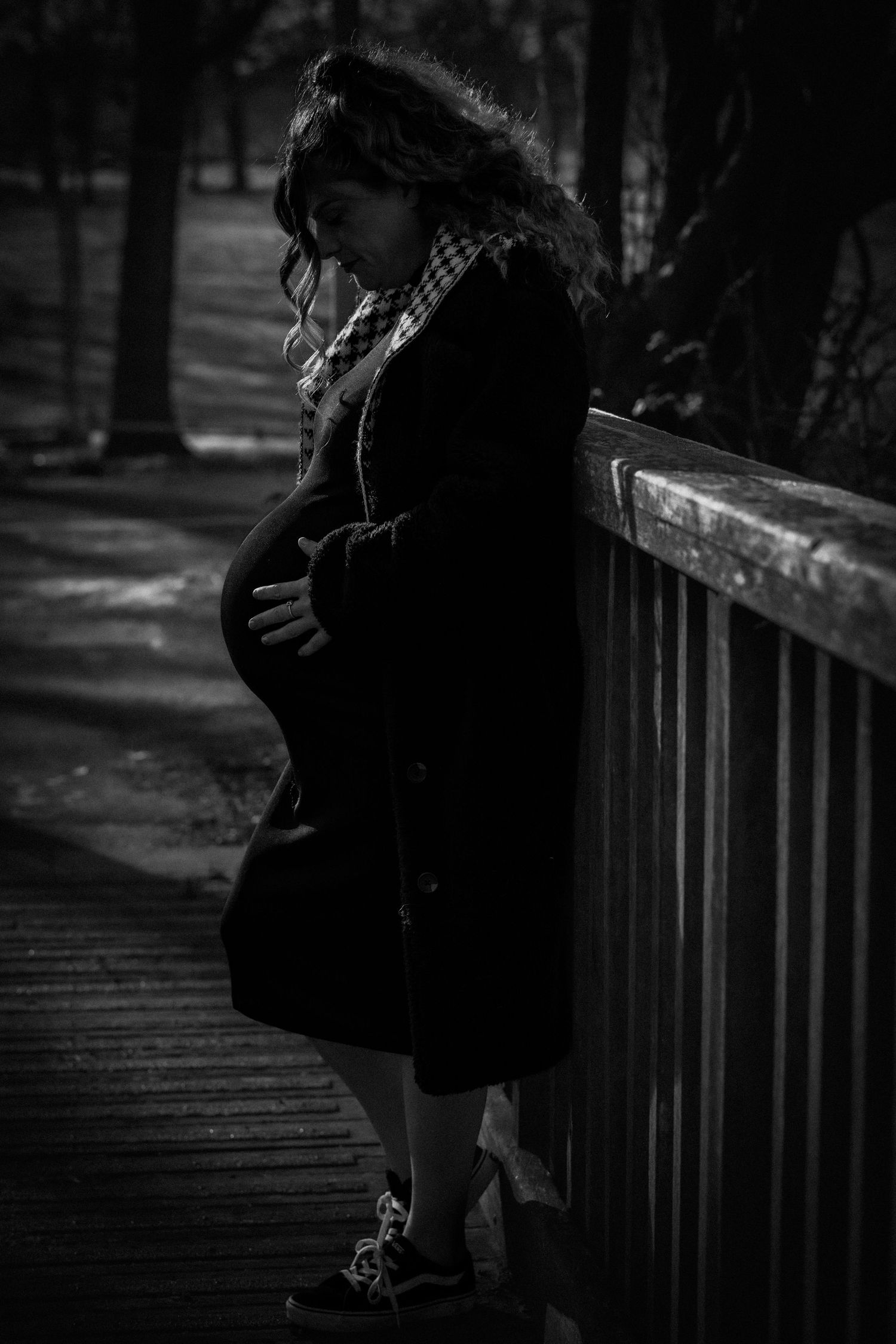 Silhouetted figures on a wooden bridge in moody black and white photography.