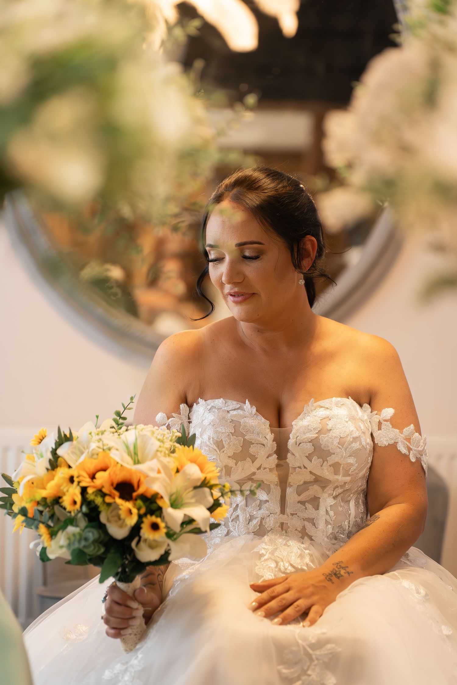 Wedding bouquet with yellow sunflowers and white flowers on white dress.