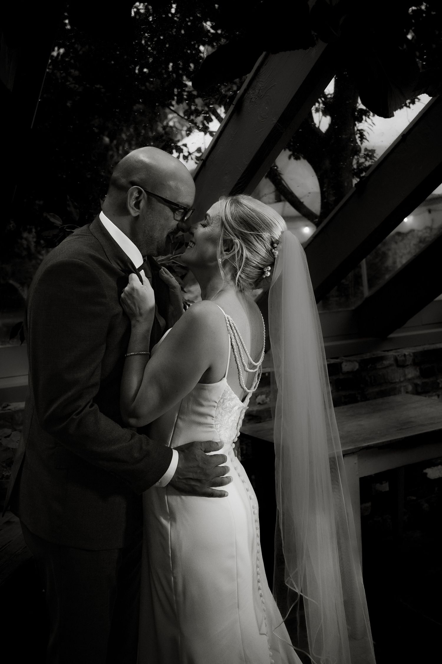 Artistic black and white wedding sequence showing intimate moments under wooden beams.