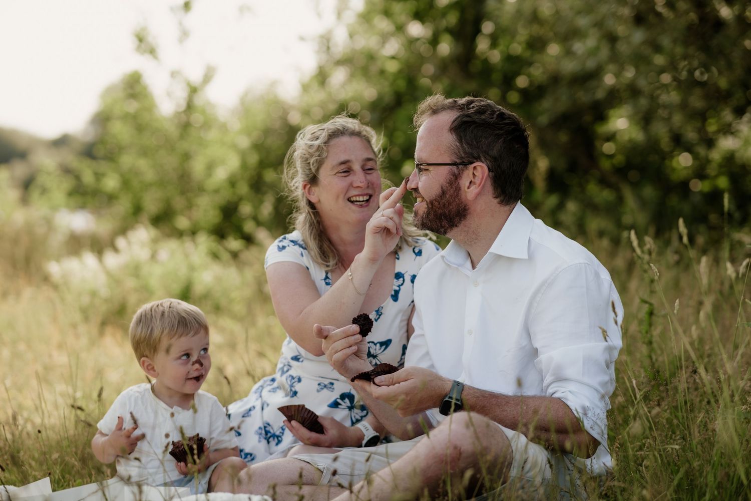 Family enjoying a tender moment together in a sunlit summer field.