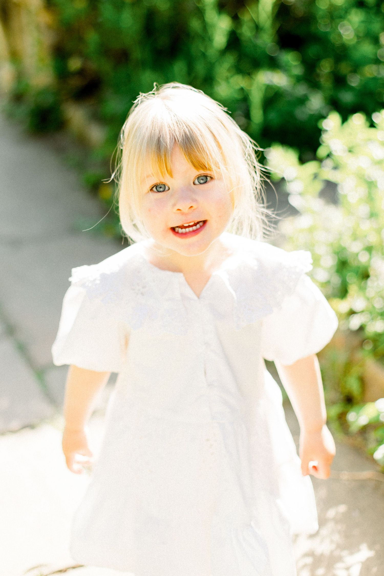 Joyful expressions captured in bright sunlight wearing white summer dress.