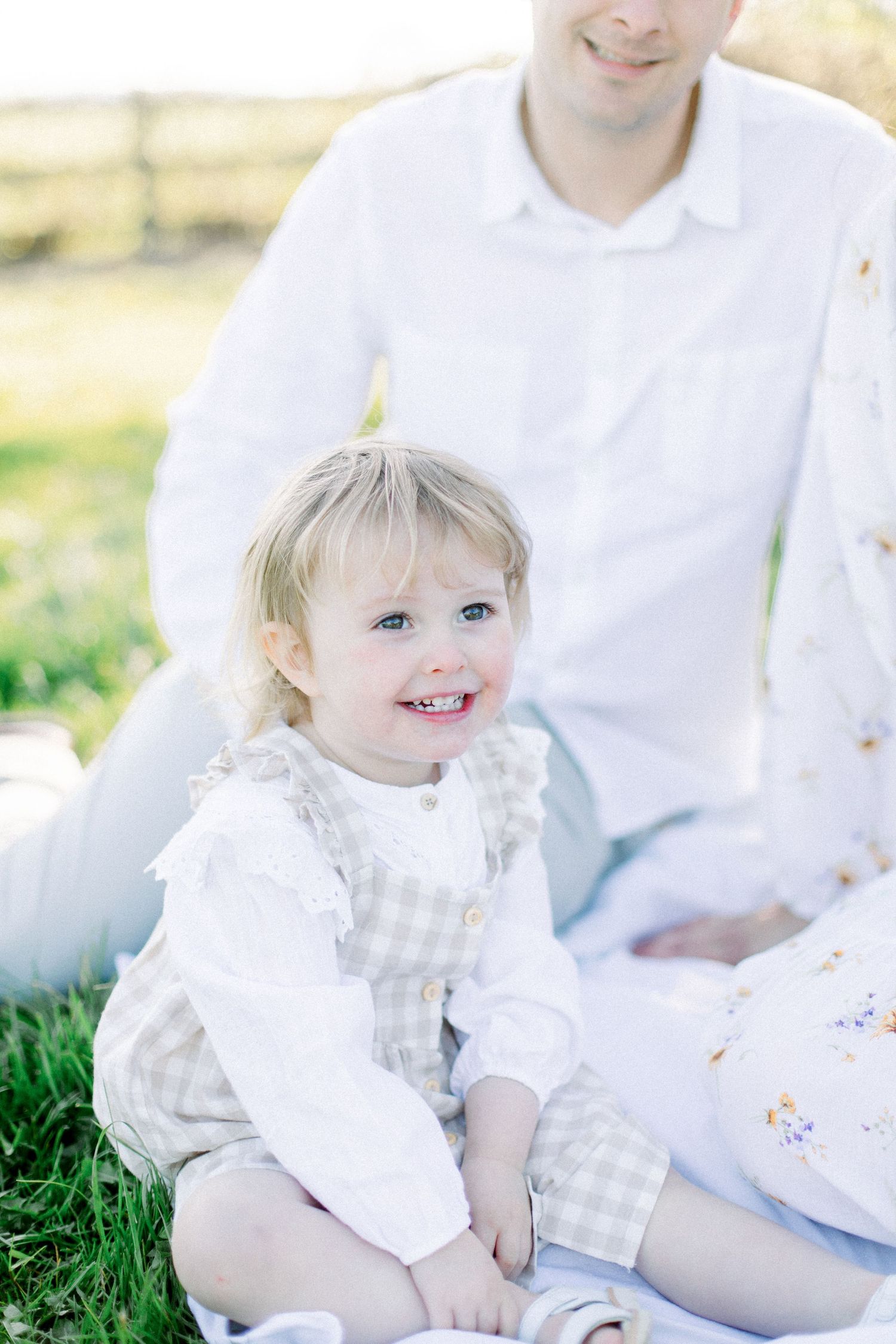 A bright outdoor portrait on grass featuring white clothing and genuine smiles.