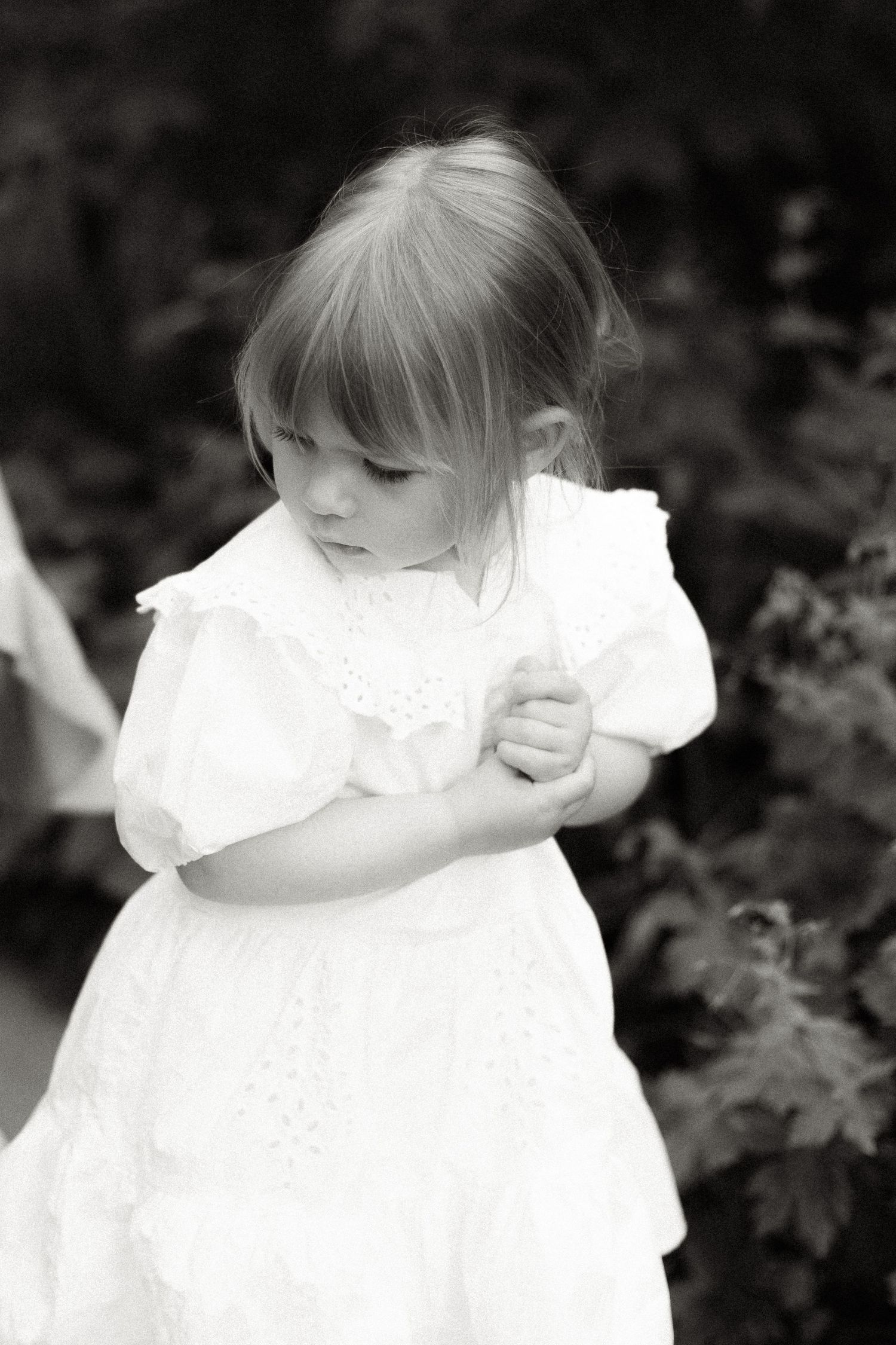 Close-up portrait of a small child in a white dress with ruffled details.