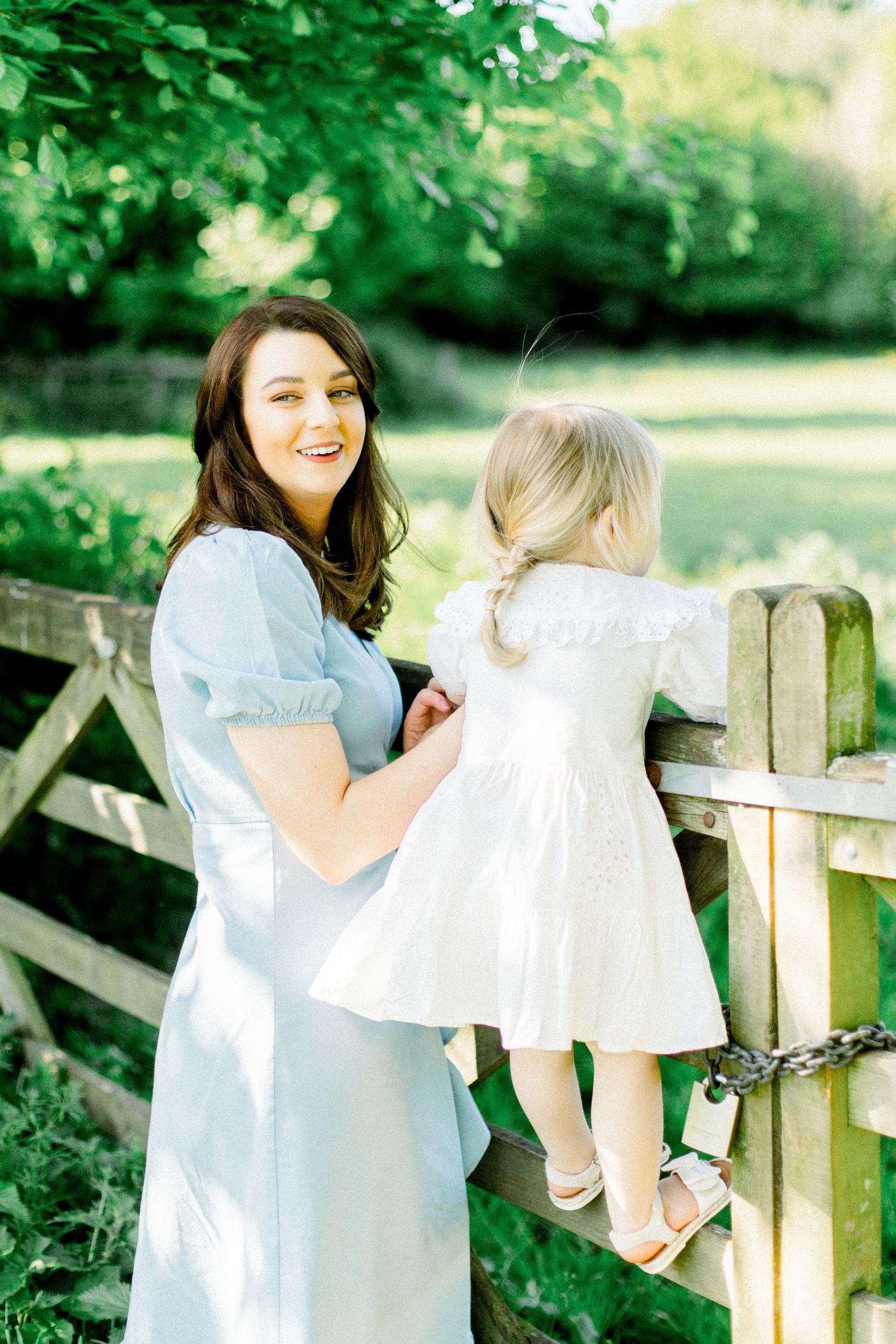Family playing and laughing together near a wooden fence in a green garden.
