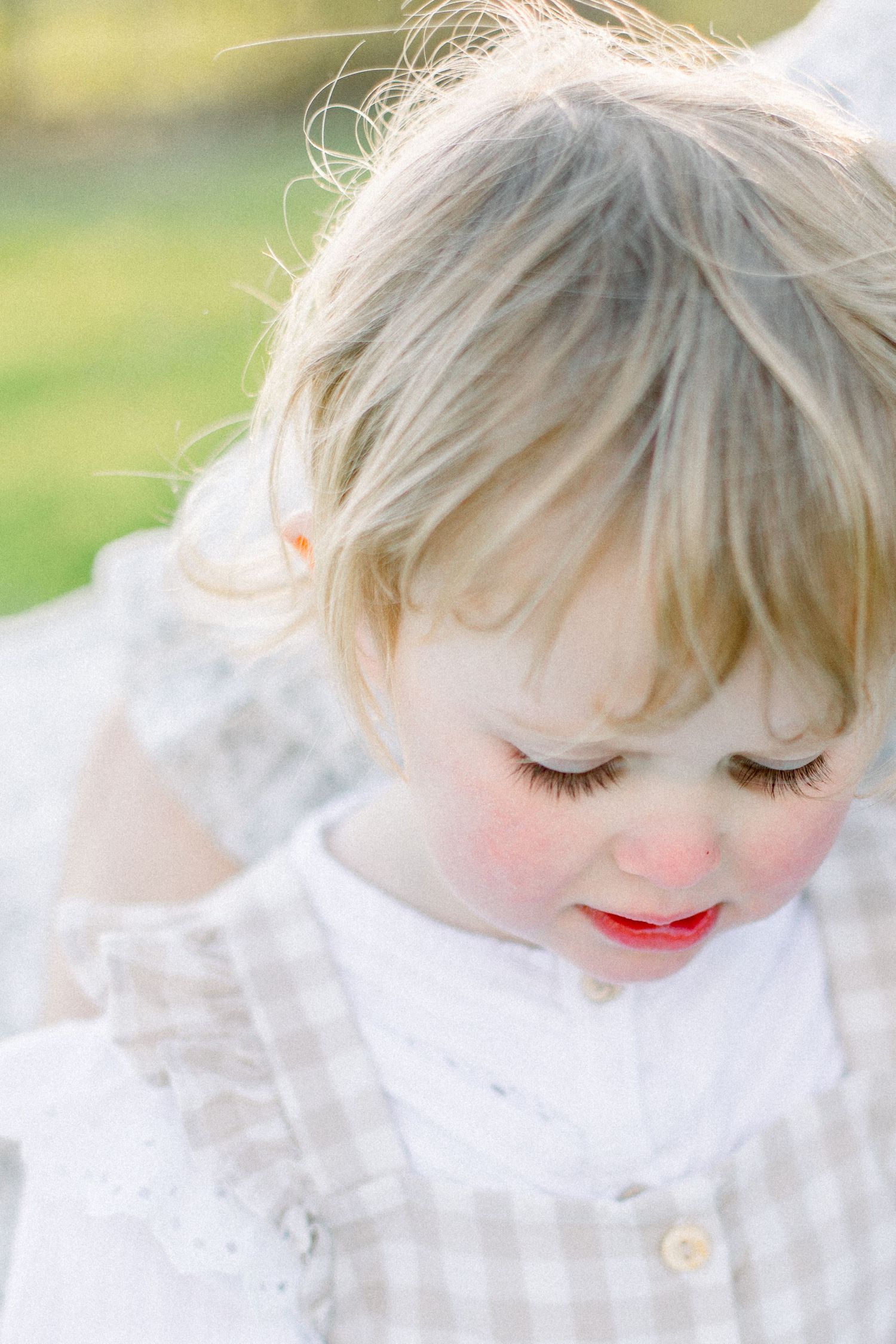Close-up portrait showing rosy cheeks and blonde hair in soft natural light.