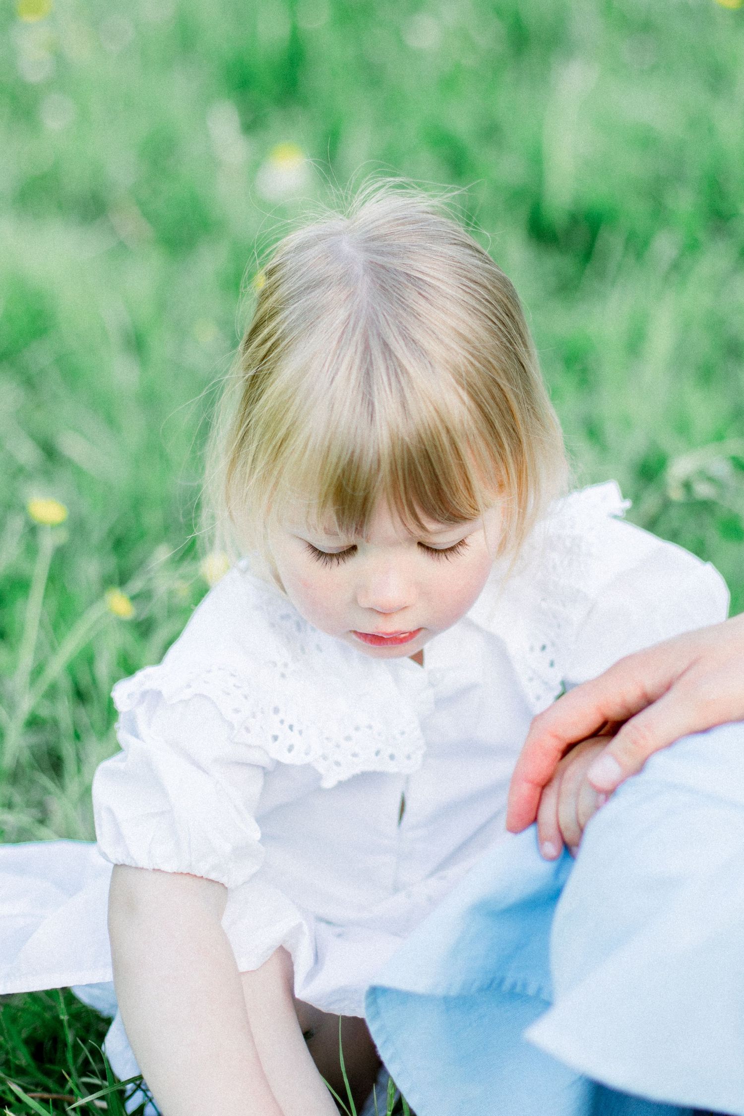 Soft ethereal portraits in white clothing against vibrant green grass background.