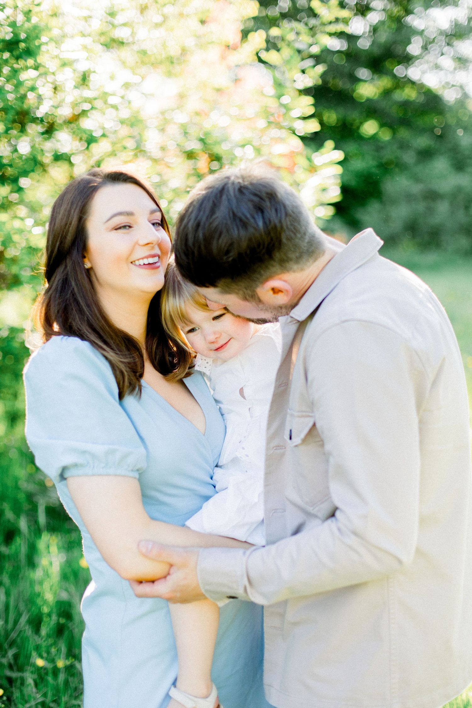 Family sharing tender moments together in a sunny garden setting.
