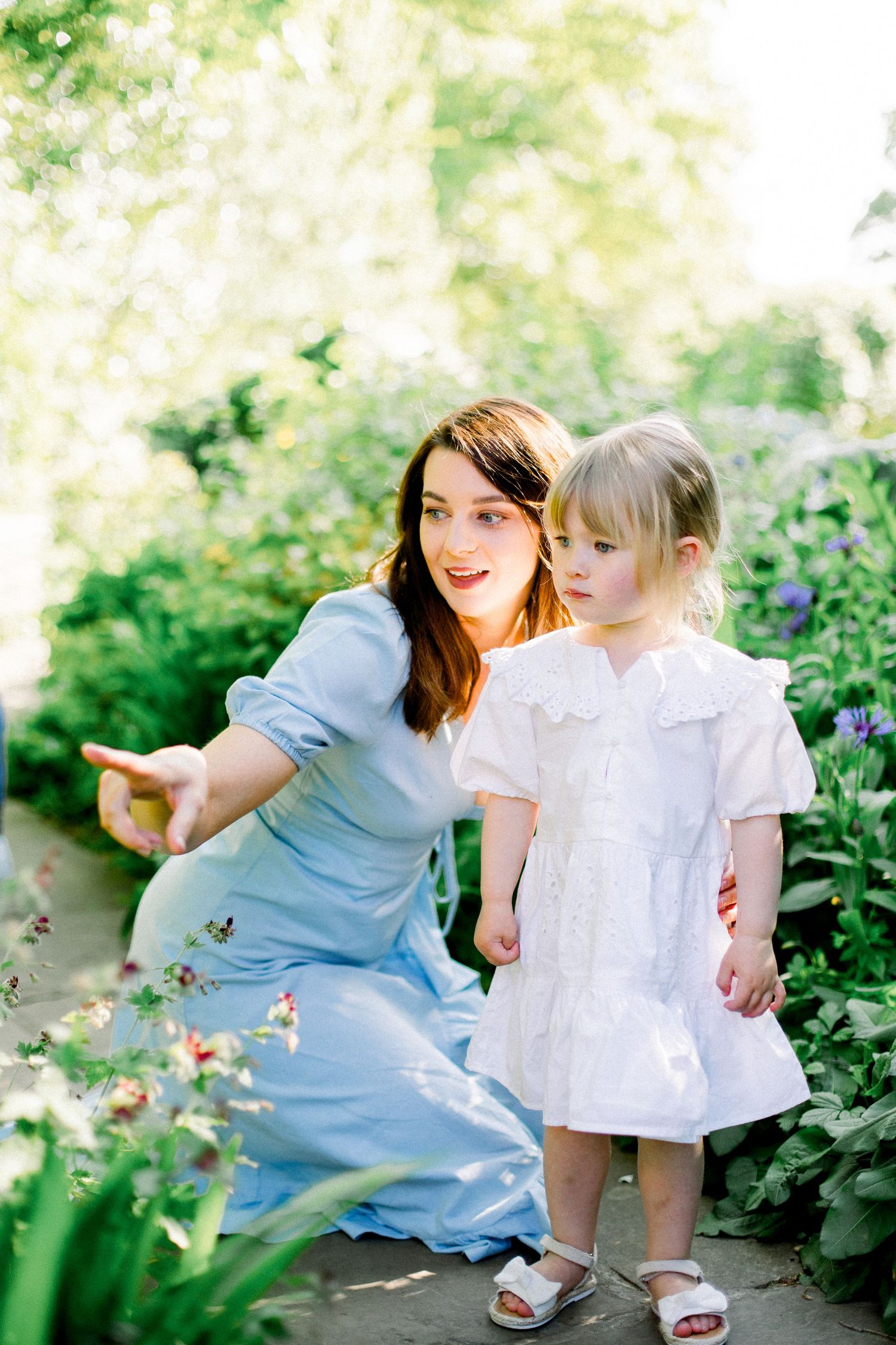 Tender outdoor moment between two people among purple flowers in a garden setting.