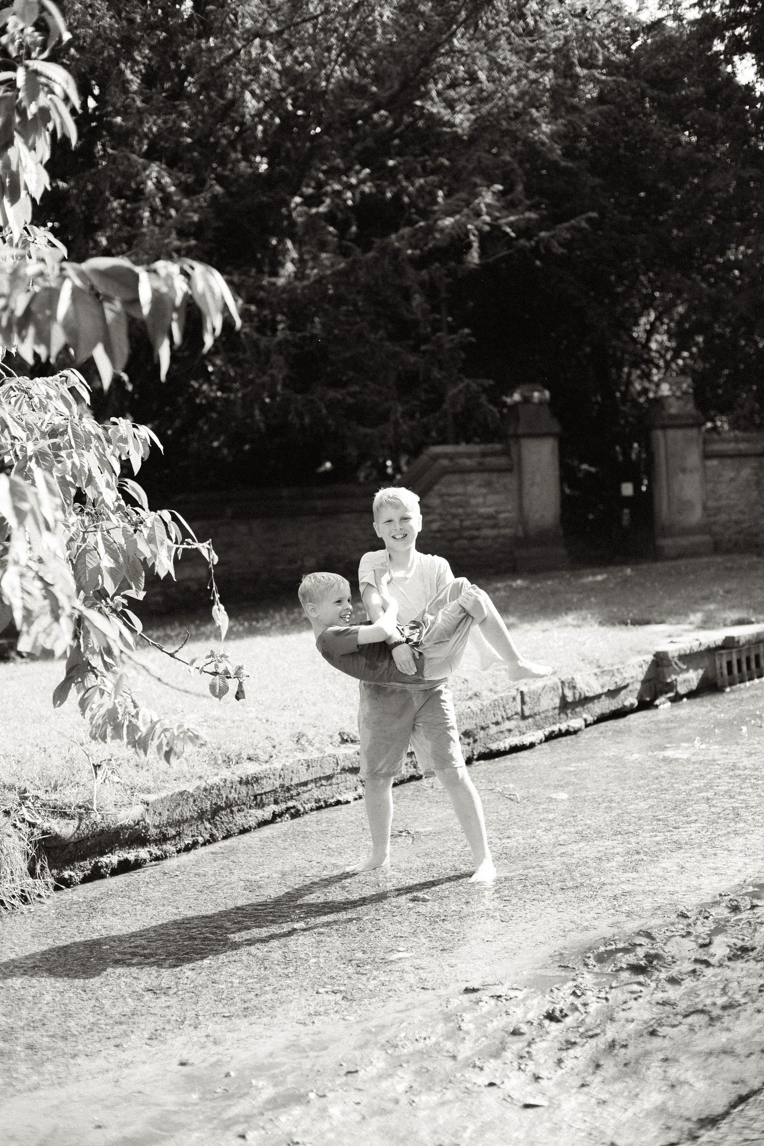 Black and white photo of child playing outdoors near garden path.