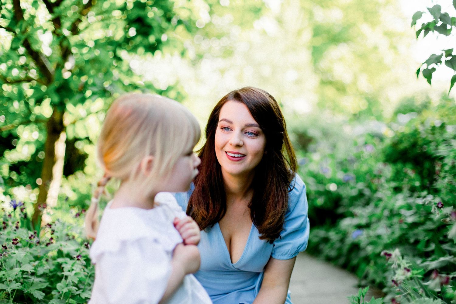 Candid family moments captured in a sunlit garden setting with natural greenery.