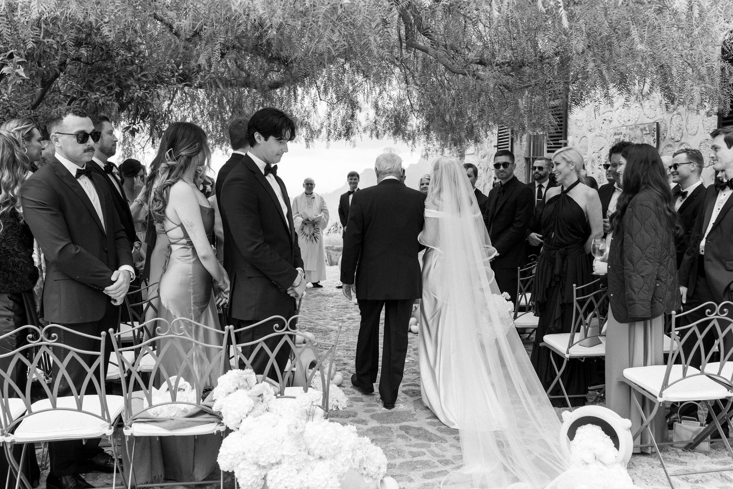 Black and white panoramic collage of an outdoor wedding ceremony showing guests seated in rows among trees.