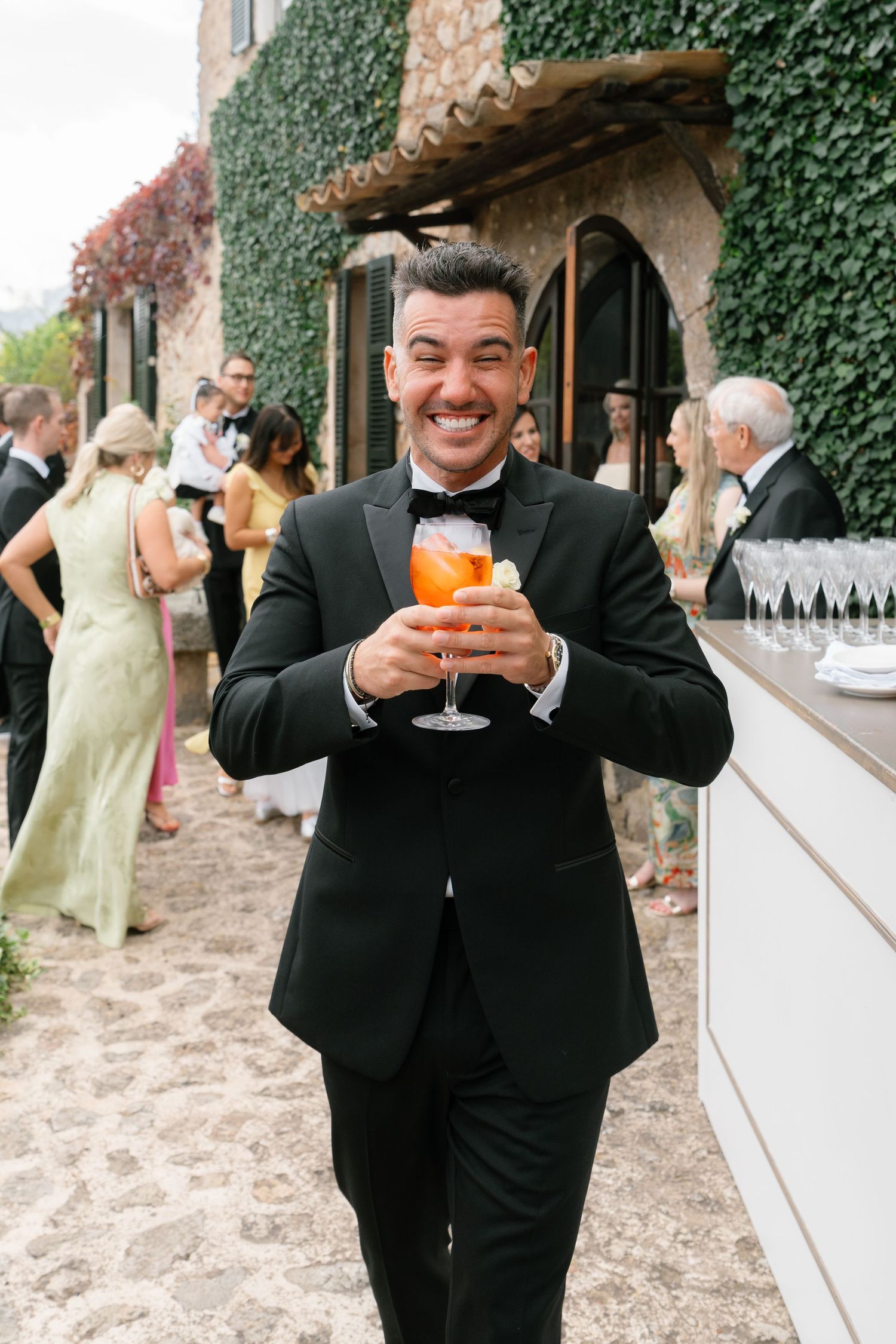 Wedding guests in formal attire enjoying cocktails at an outdoor reception.
