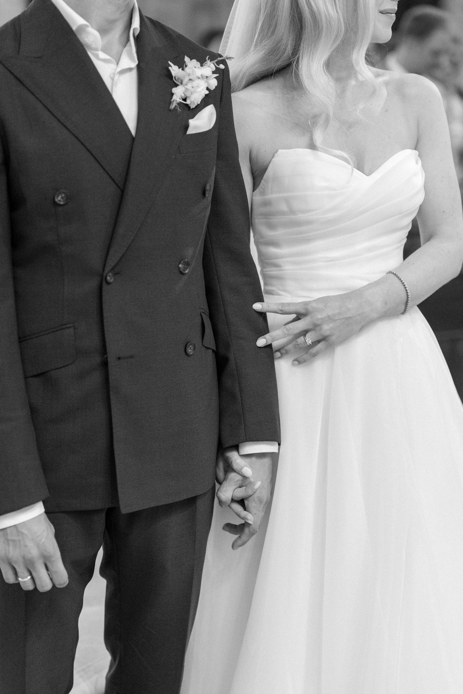 Close-up details of formal wedding attire showing white bridal gown and black suits.