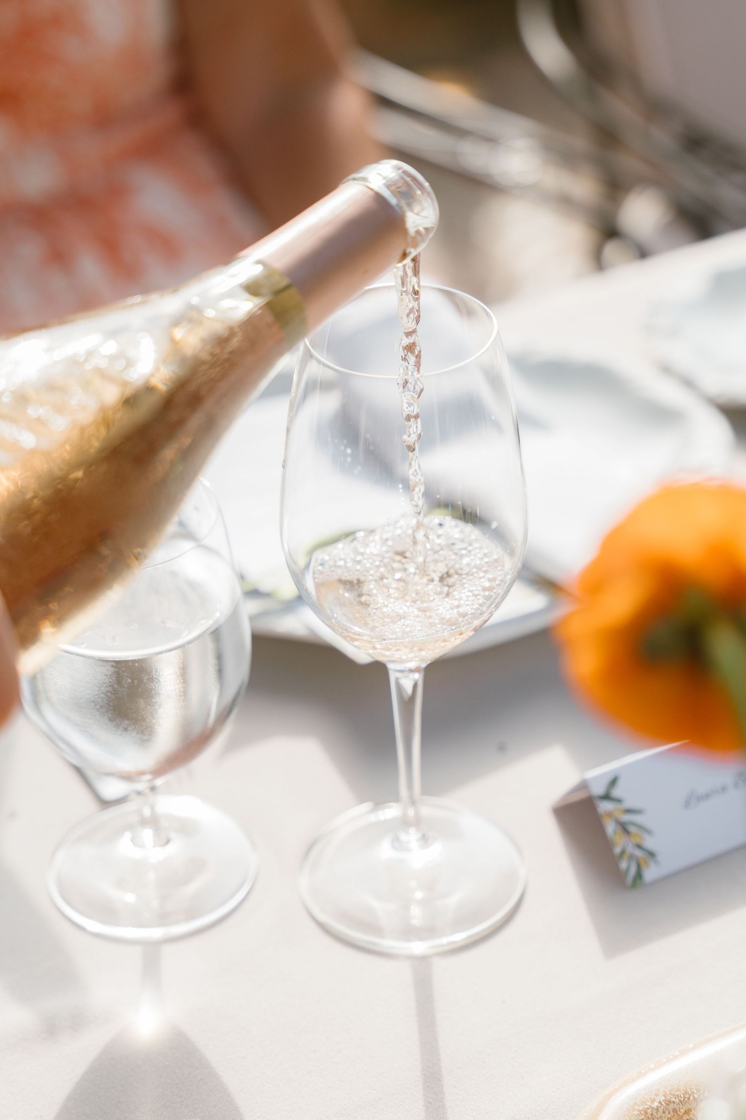 Crystal wine glasses catching sunlight on an elegant white tablecloth setting.