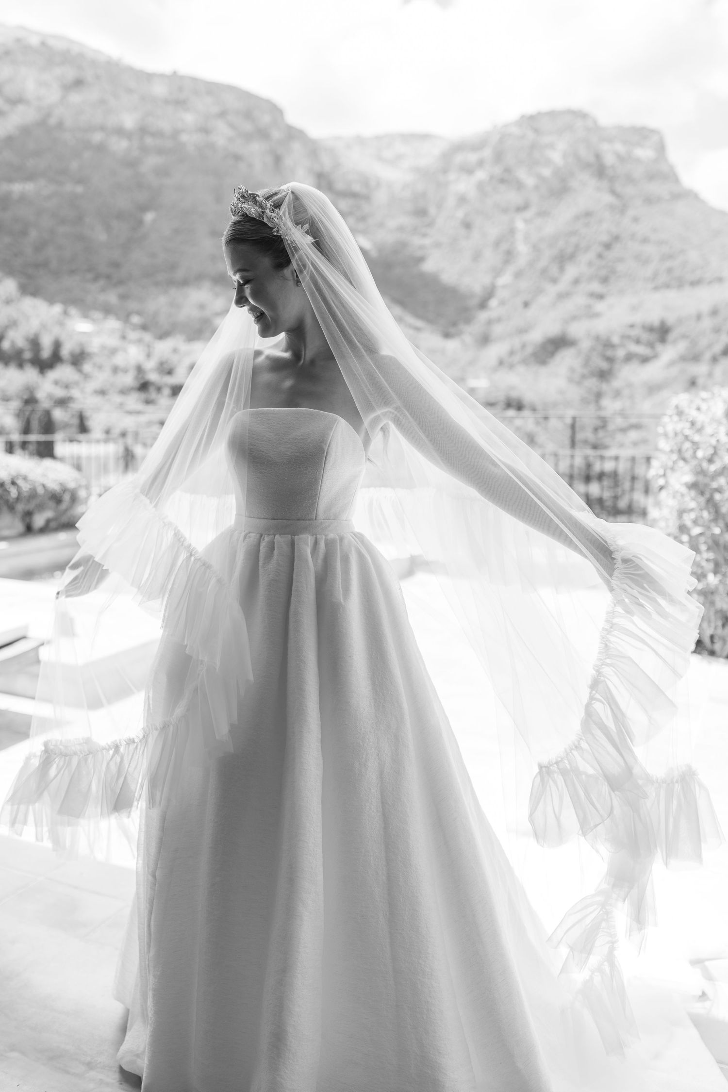 Flowing white wedding dress veil billowing in the breeze against a mountainous backdrop.