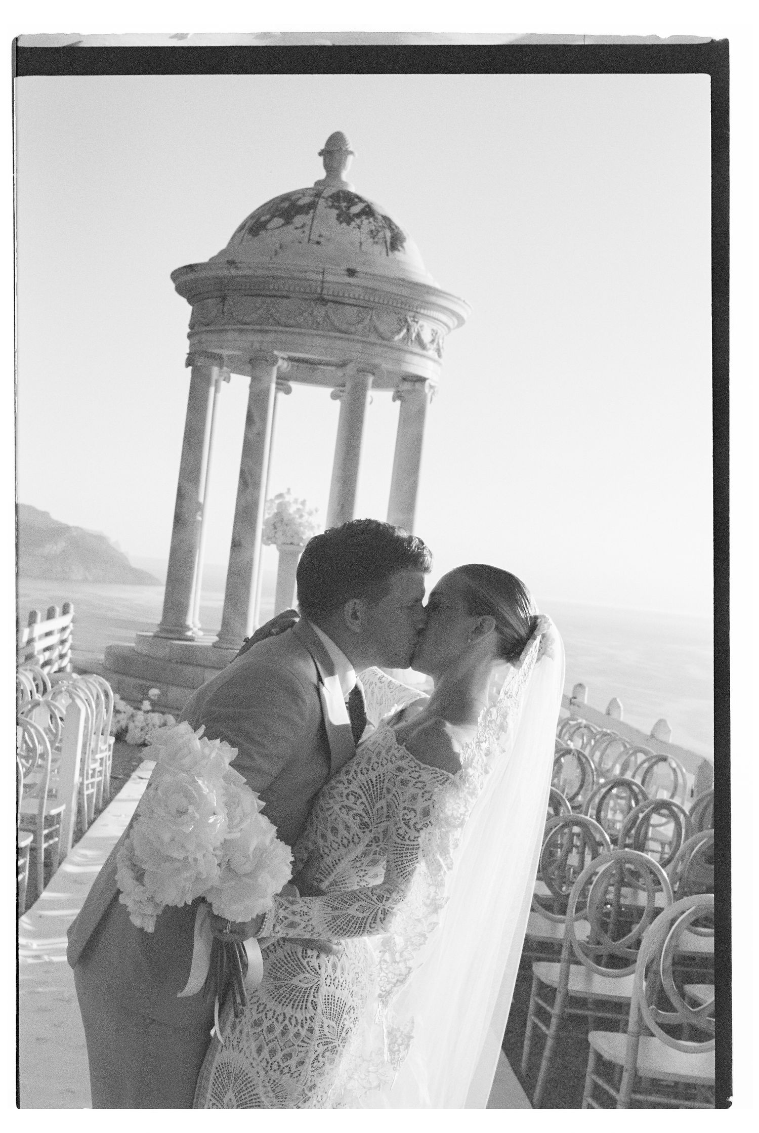 Romantic wedding ceremony setup with classical pillared structure and floral arrangements.