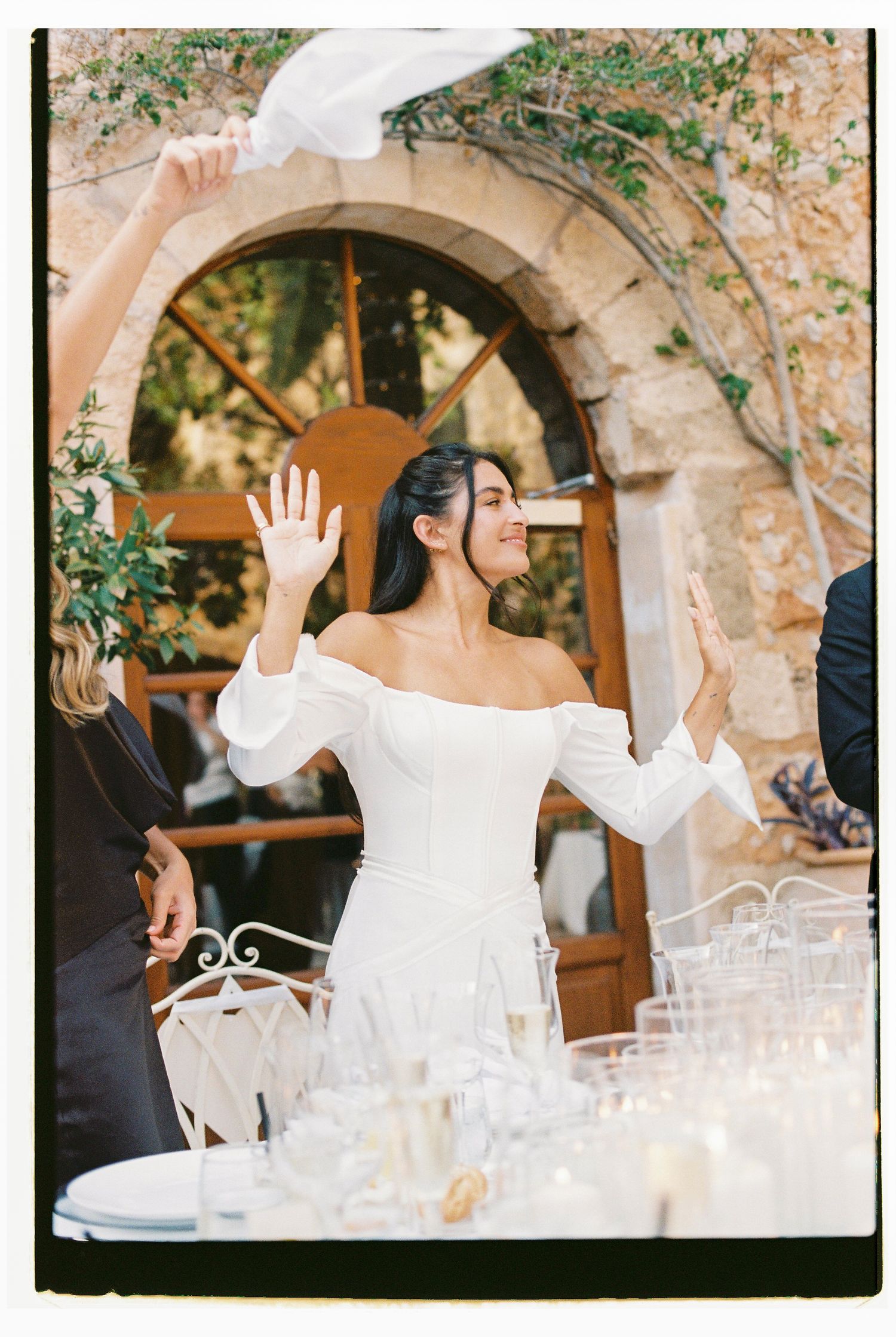 A wedding celebration at a Mediterranean villa with white off-shoulder dress and champagne glasses on display.