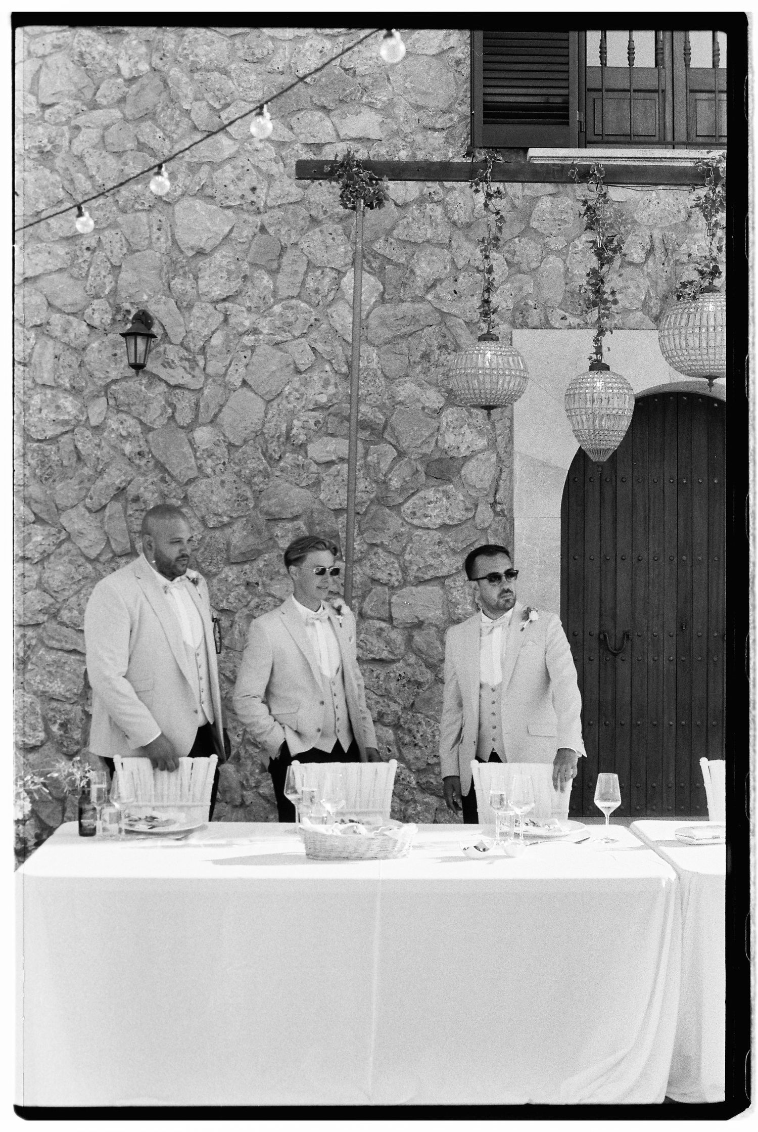 A formal dining setup with a white tablecloth against a stone wall backdrop.