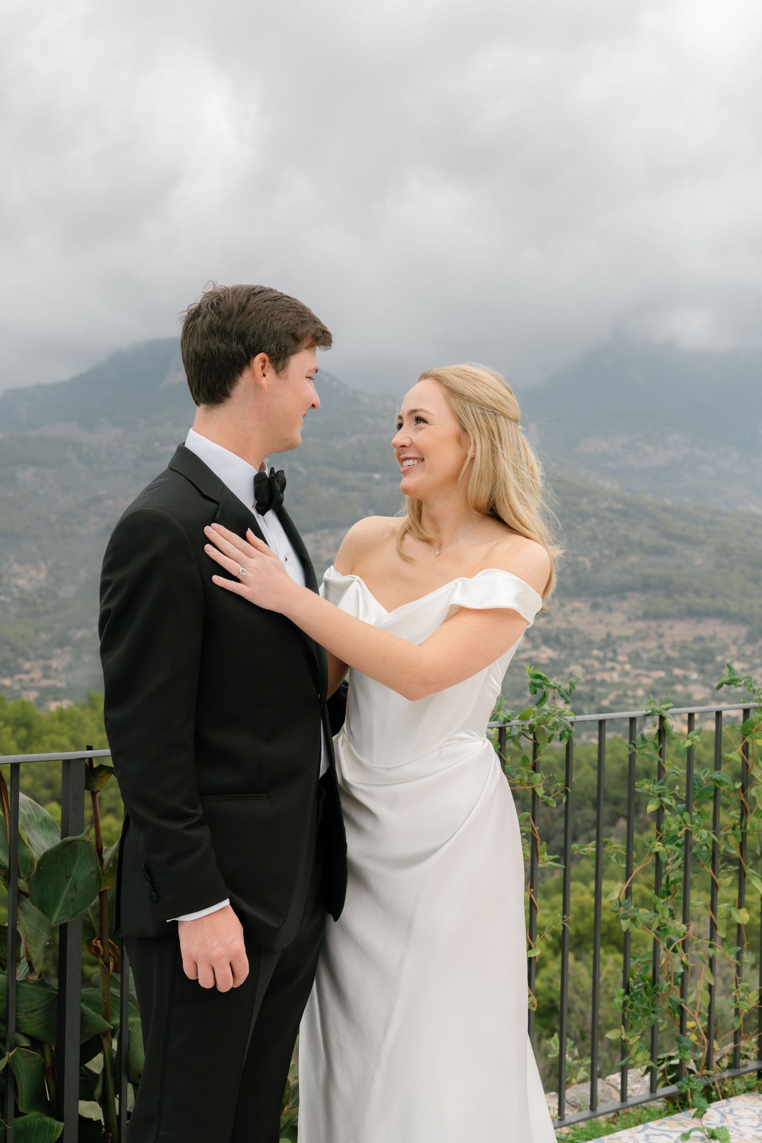 Couple in wedding attire share intimate moments on a scenic mountain overlook.