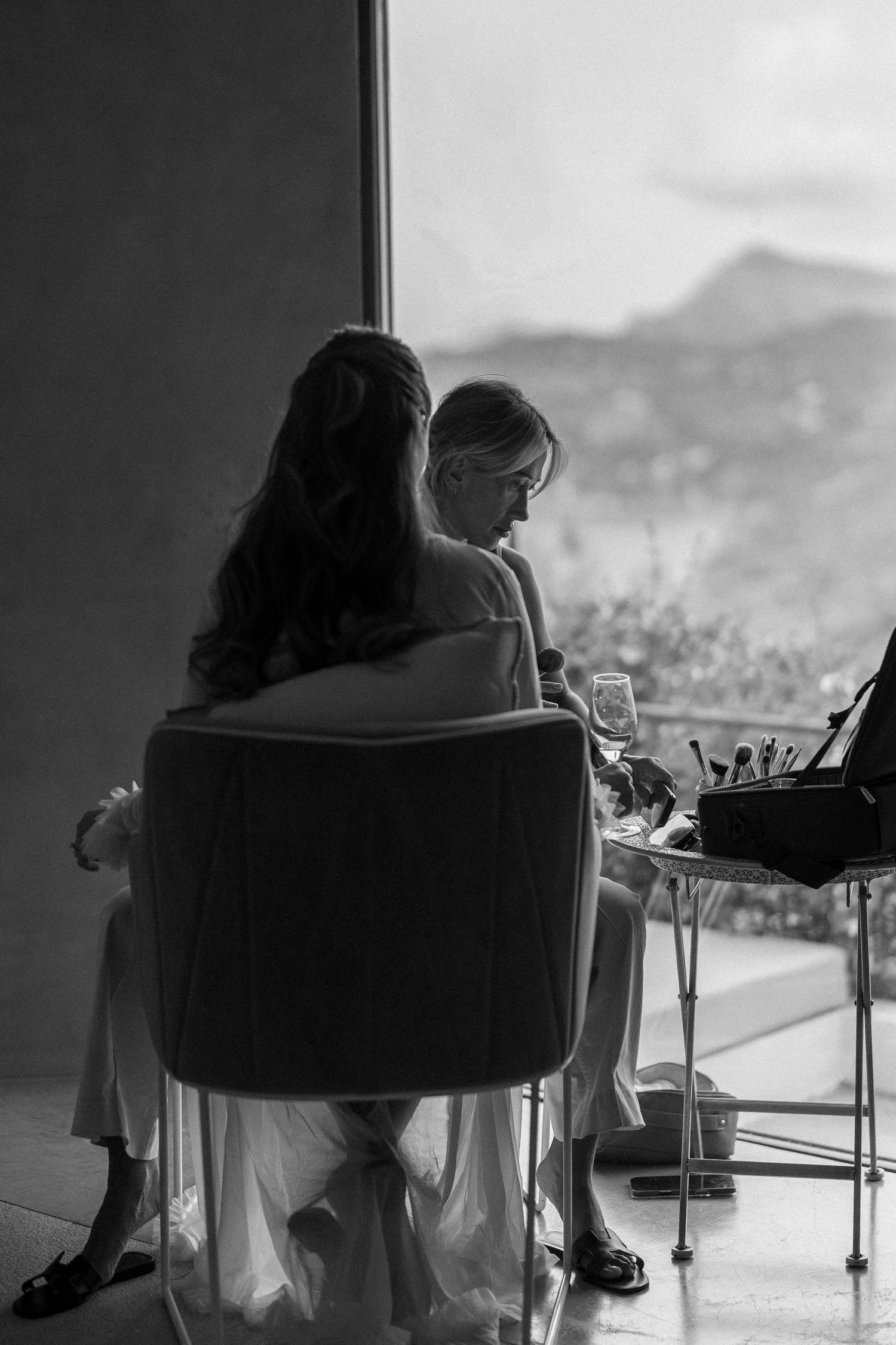 Black and white photo showing a couple seated in chairs overlooking a scenic mountain vista.