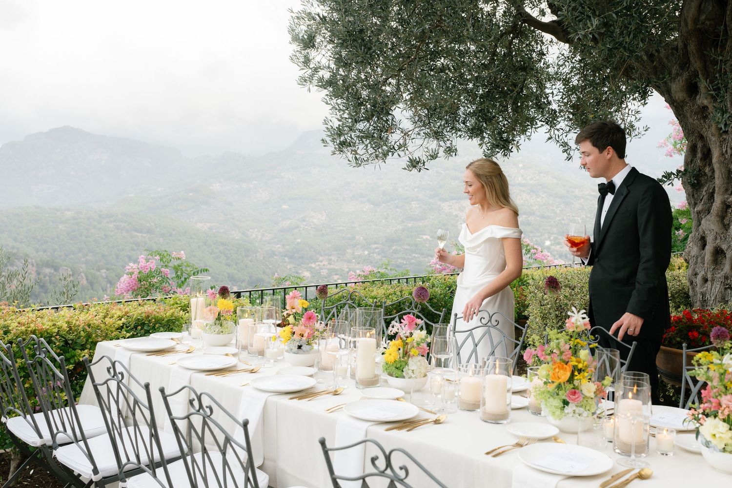 Outdoor wedding reception tables set with white linens and colorful floral centerpieces overlooking a scenic mountain view.
