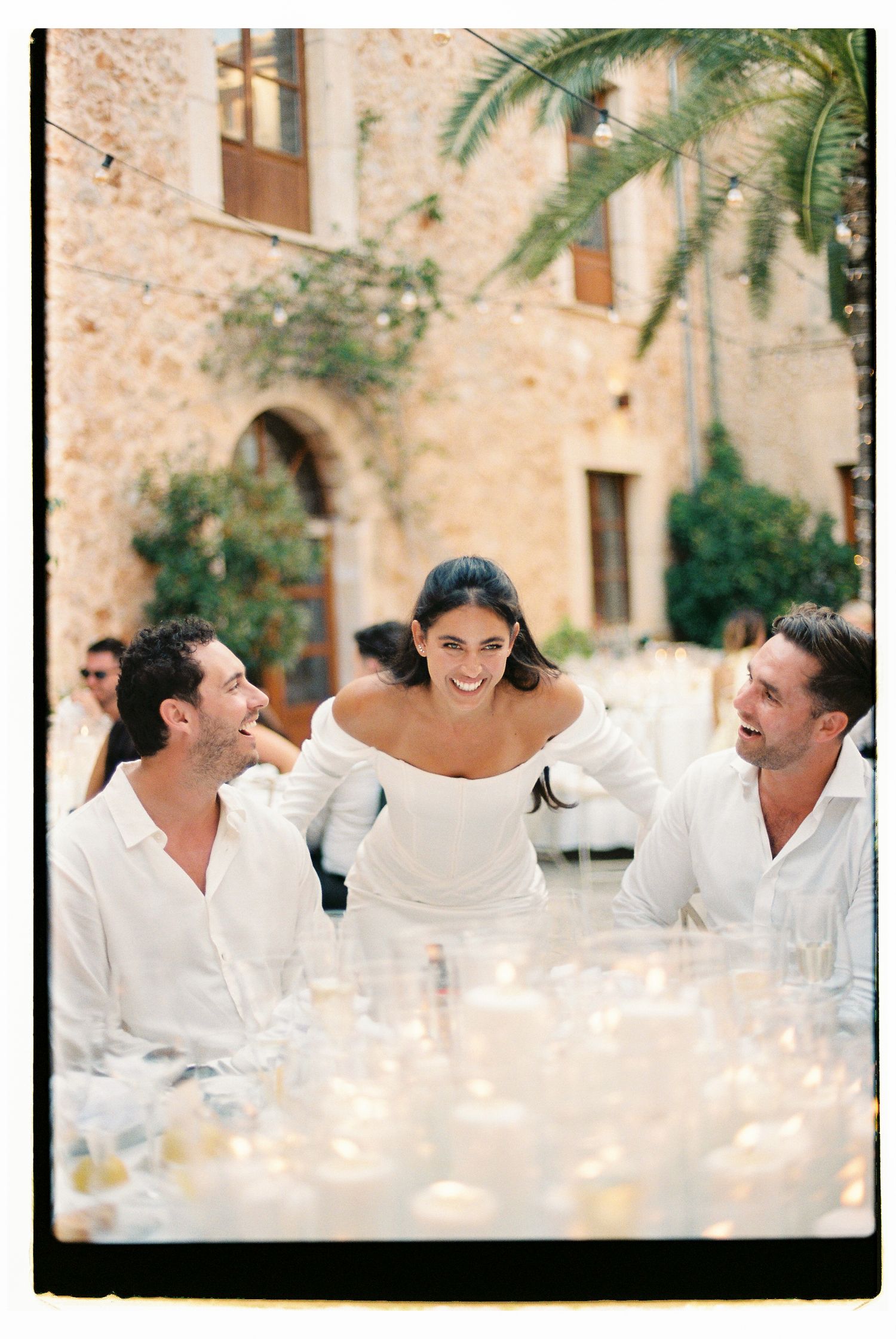 Joyful wedding celebration with white decor and candlelight at a rustic stone villa.