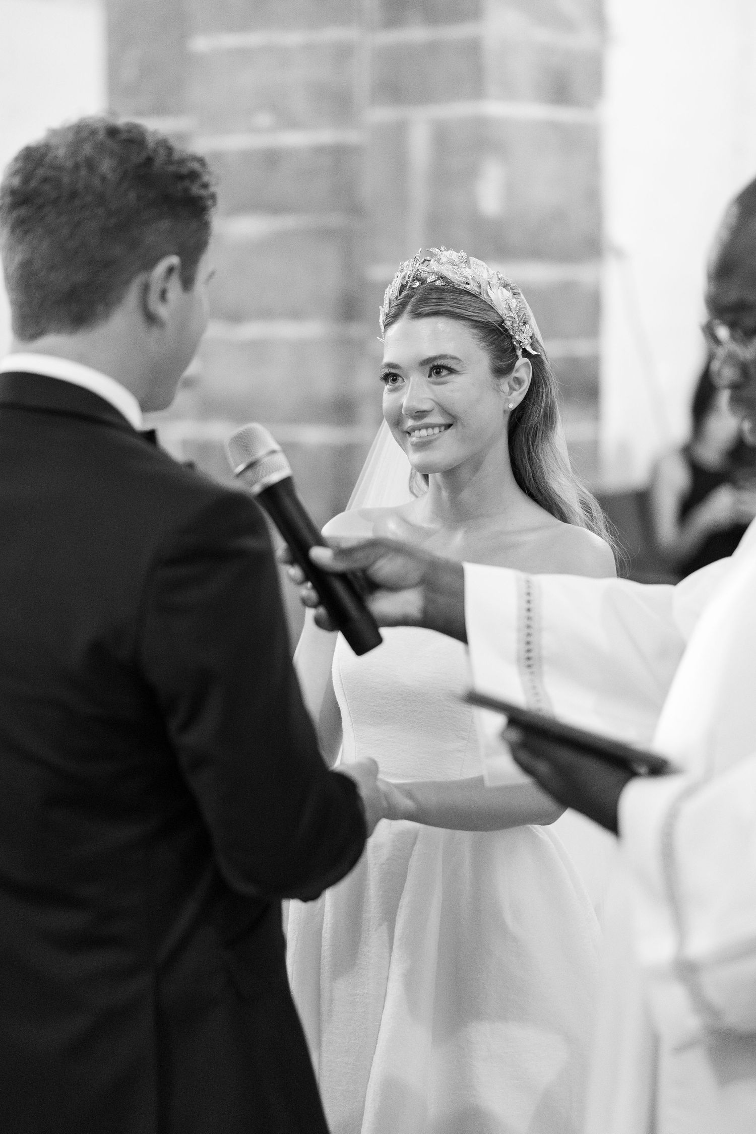 Wedding ceremony moment with couple exchanging vows in front of stone architecture.