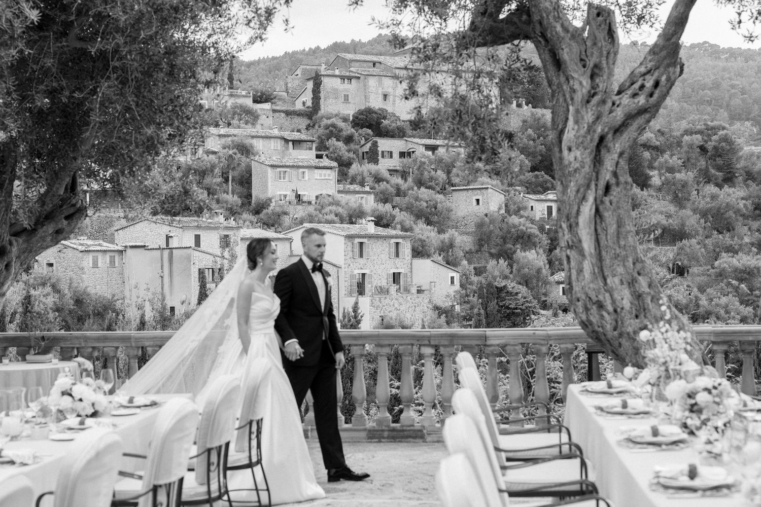 Elegant outdoor wedding reception setup with tables and chairs on a terrace overlooking a scenic landscape.