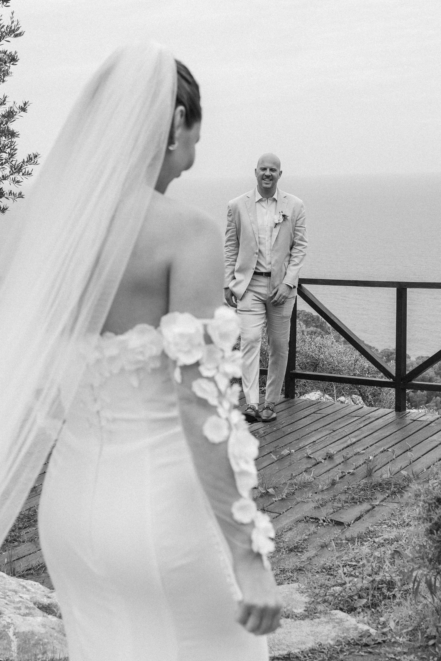 Black and white first look moment captured on scenic coastal overlook.