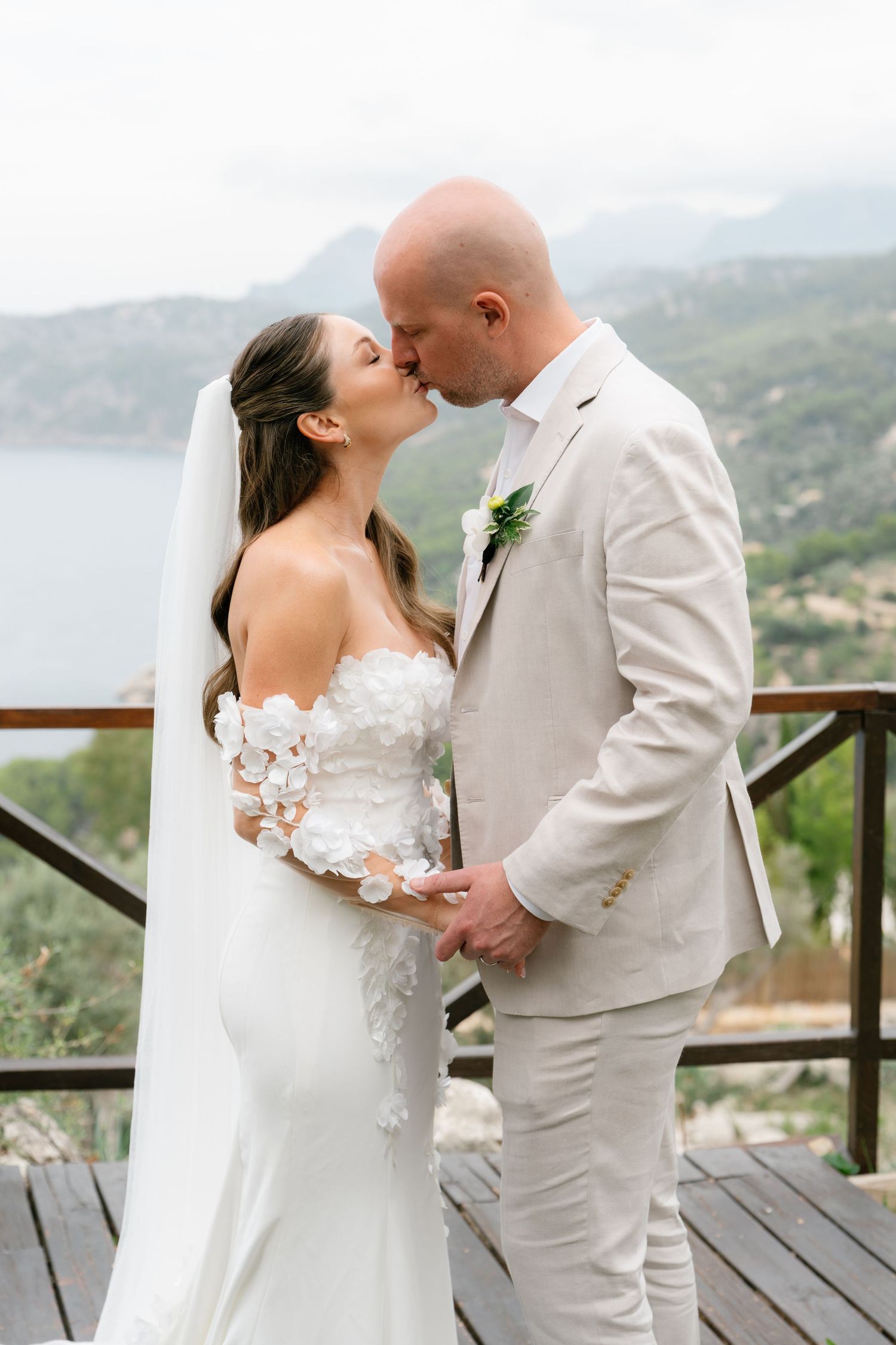 Intimate wedding portraits captured on a wooden deck with Mediterranean coastal scenery.