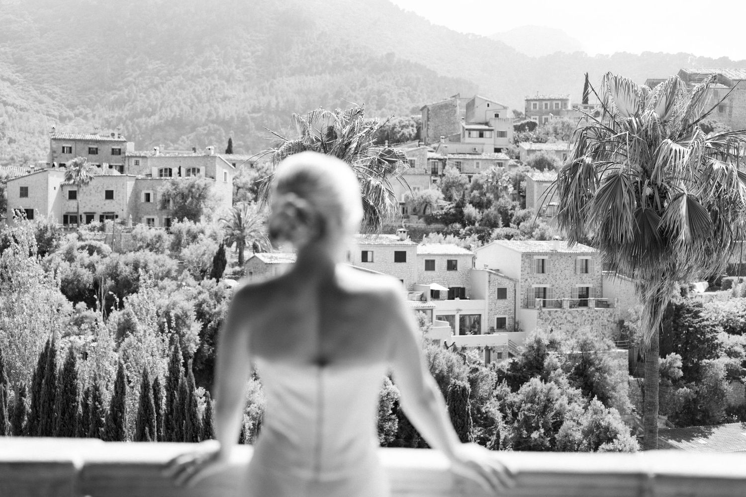 Mediterranean coastal town landscape with white buildings and mountains in the background.
